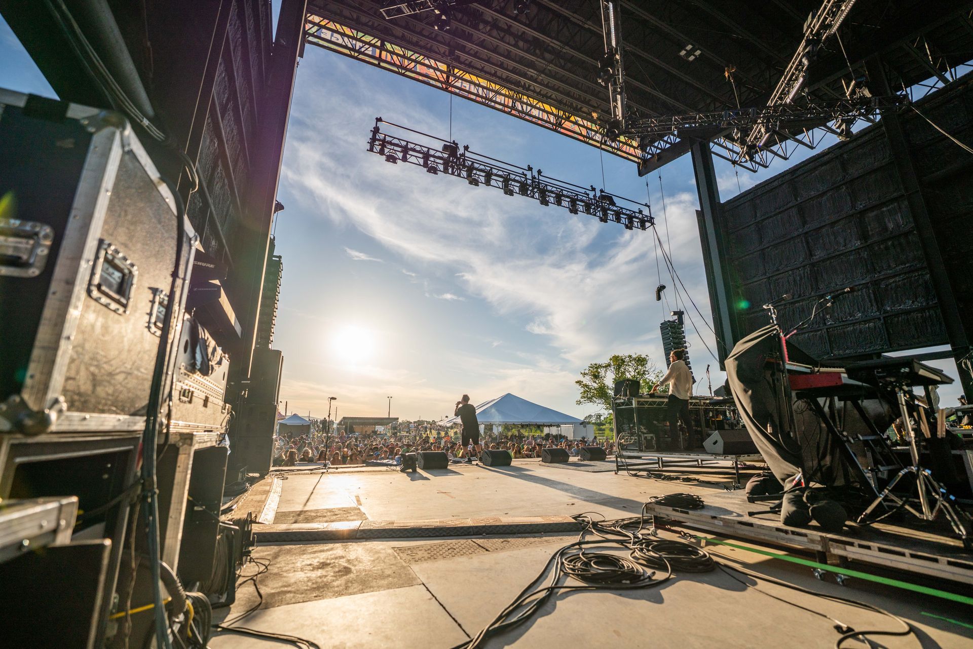 A stage is being set up for a concert with the sun shining through the roof.