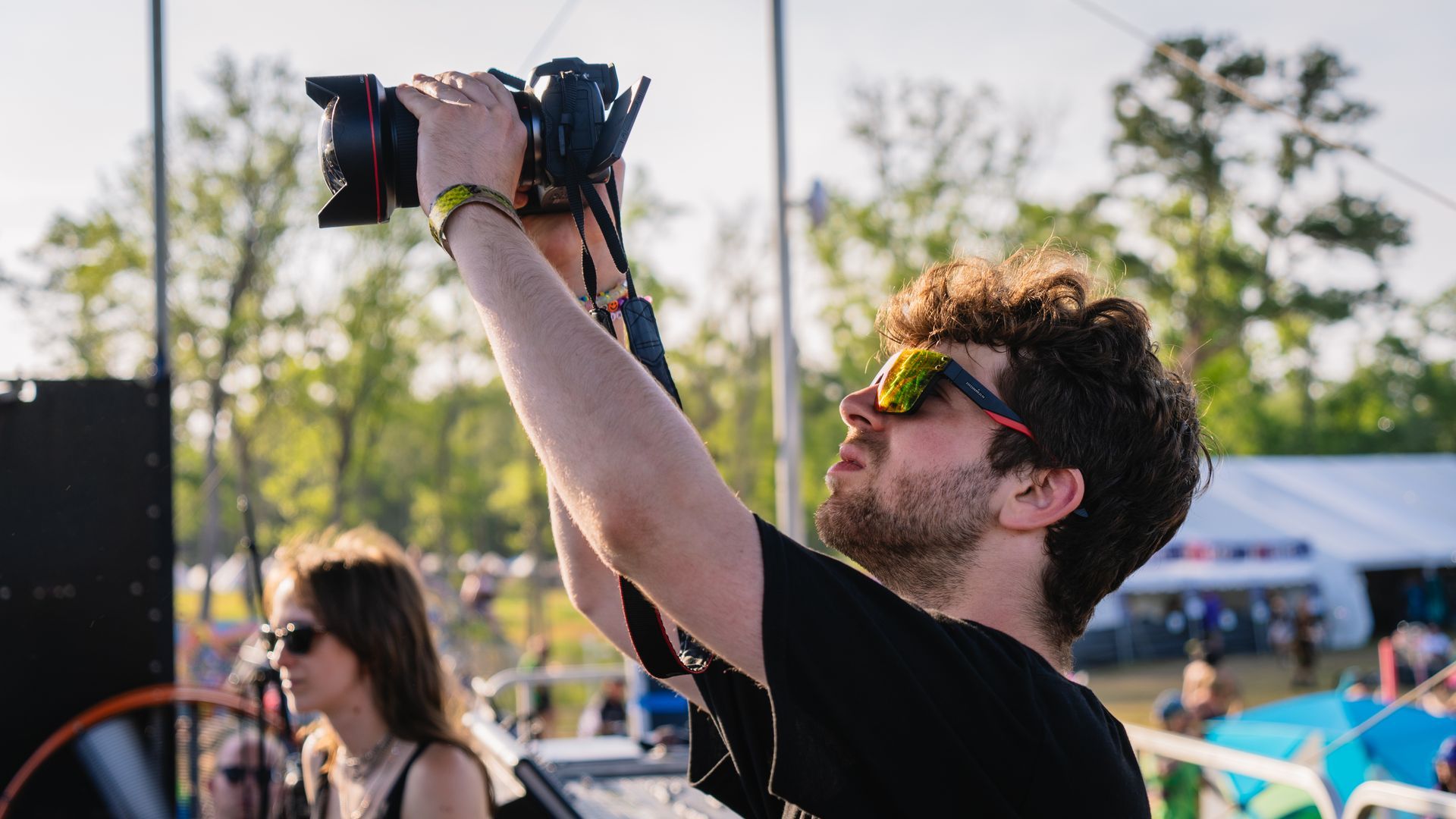 A man is taking a picture with a camera at a festival.