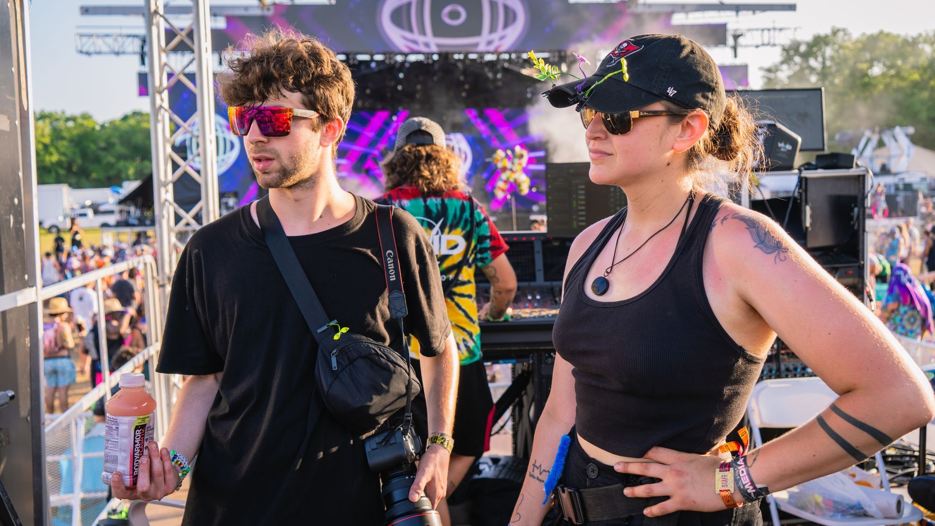 A man and a woman are standing next to each other at a music festival.