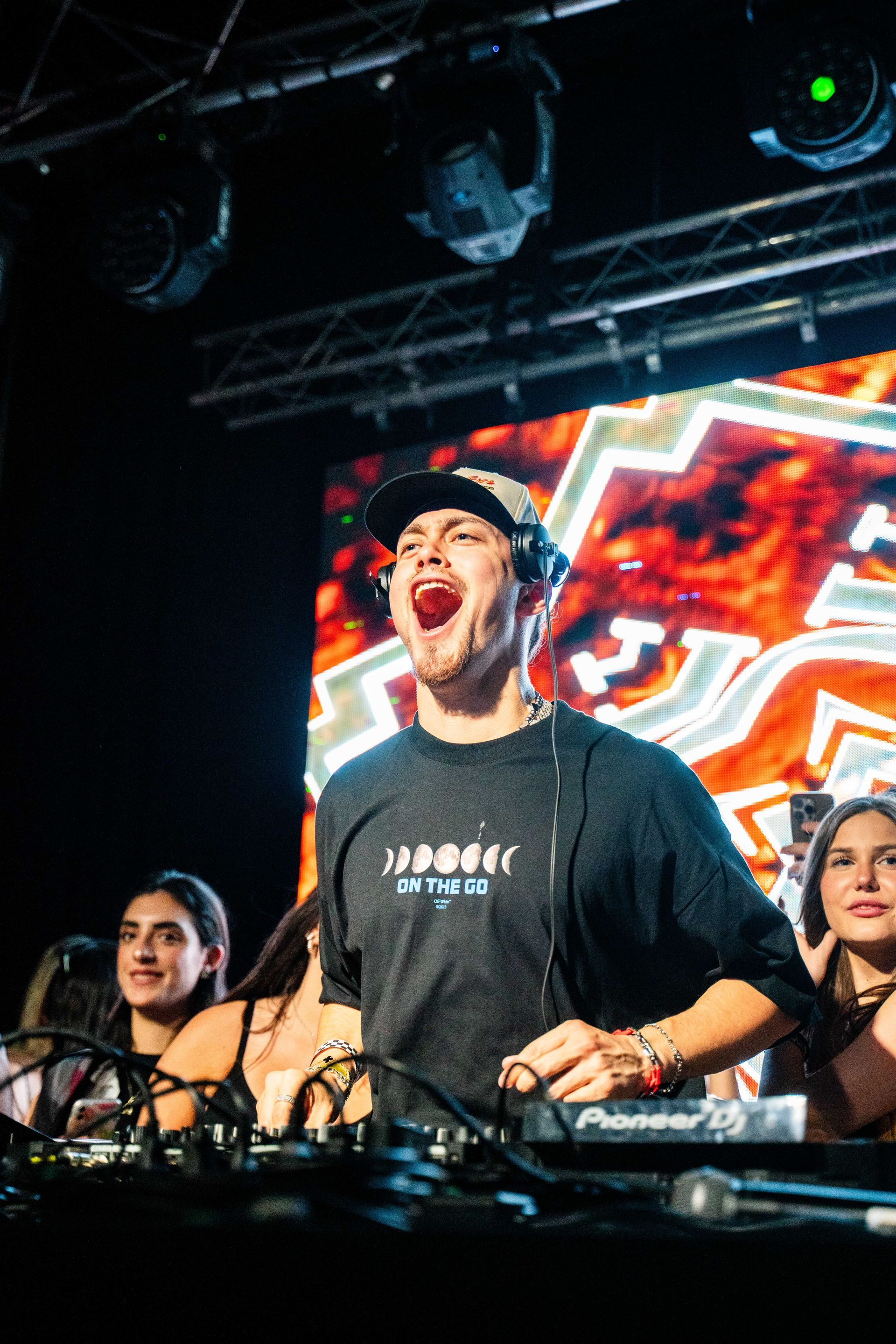 A dj is playing music on a stage in front of a crowd of people.
