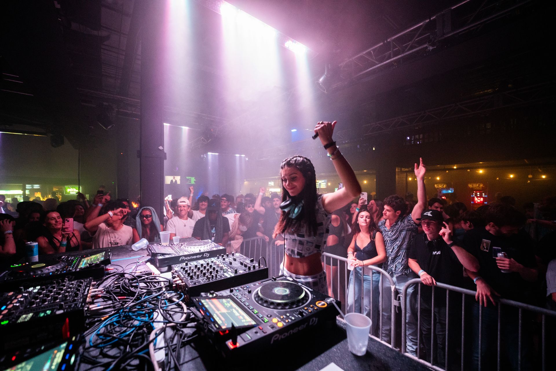 A woman is playing music in front of a crowd in a club.