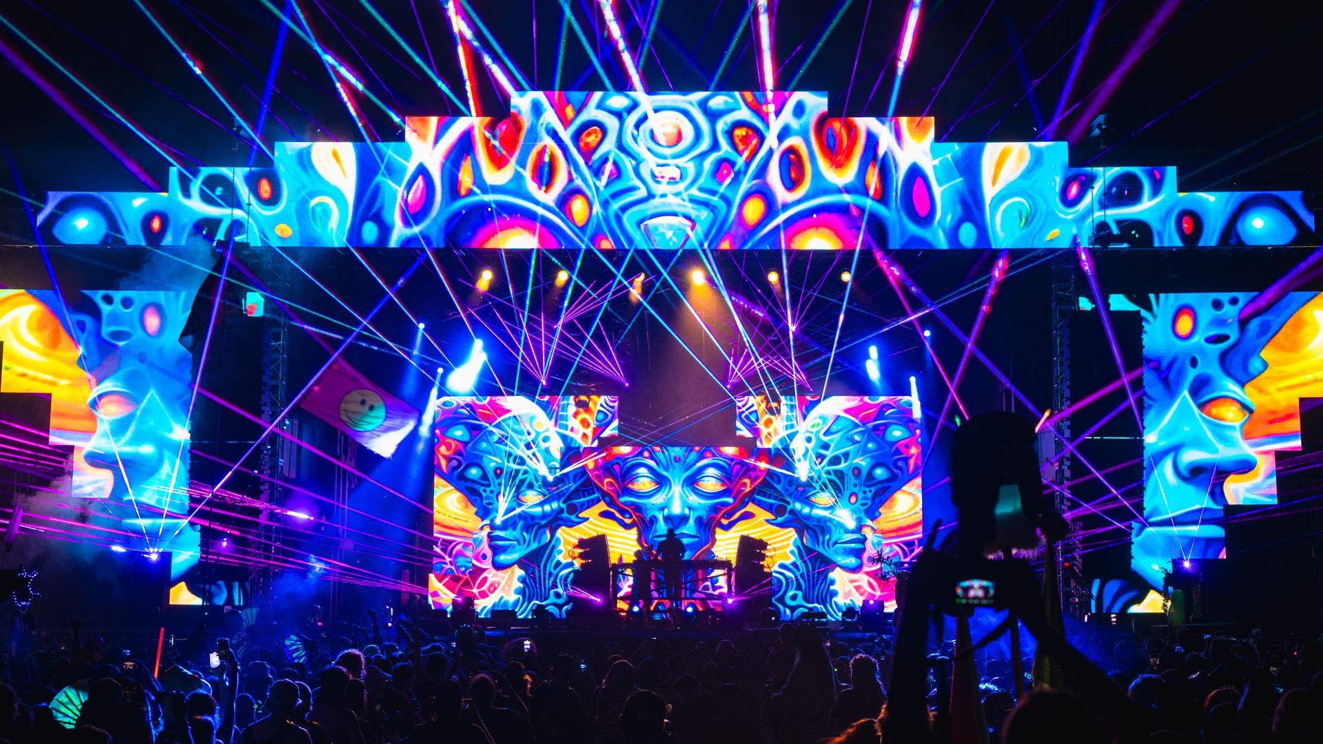 A crowd of people are standing in front of a stage at a concert.