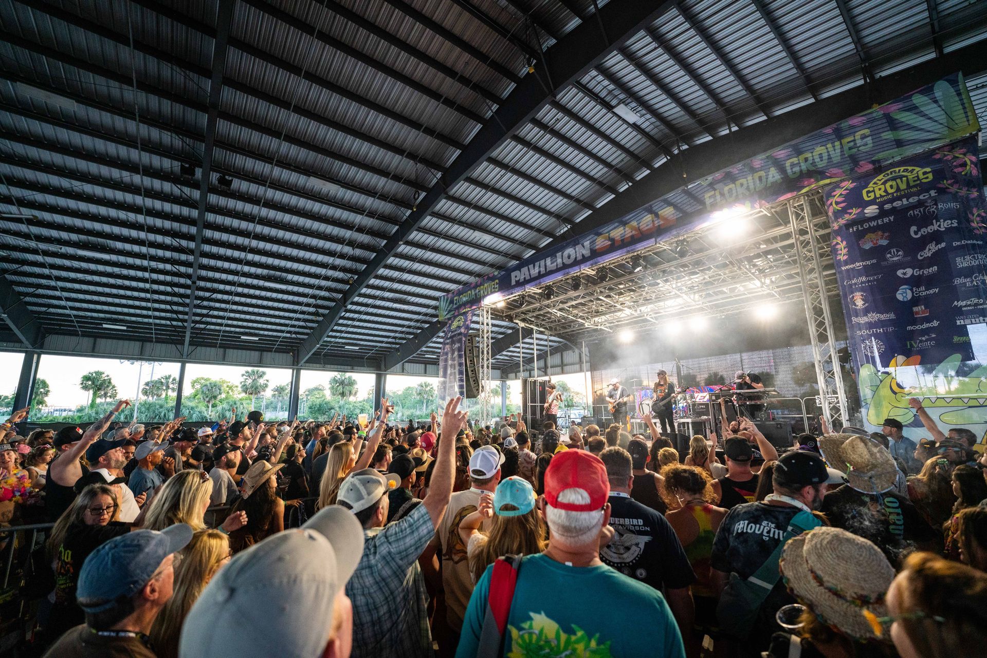 A large crowd of people are watching a band on stage at a concert.