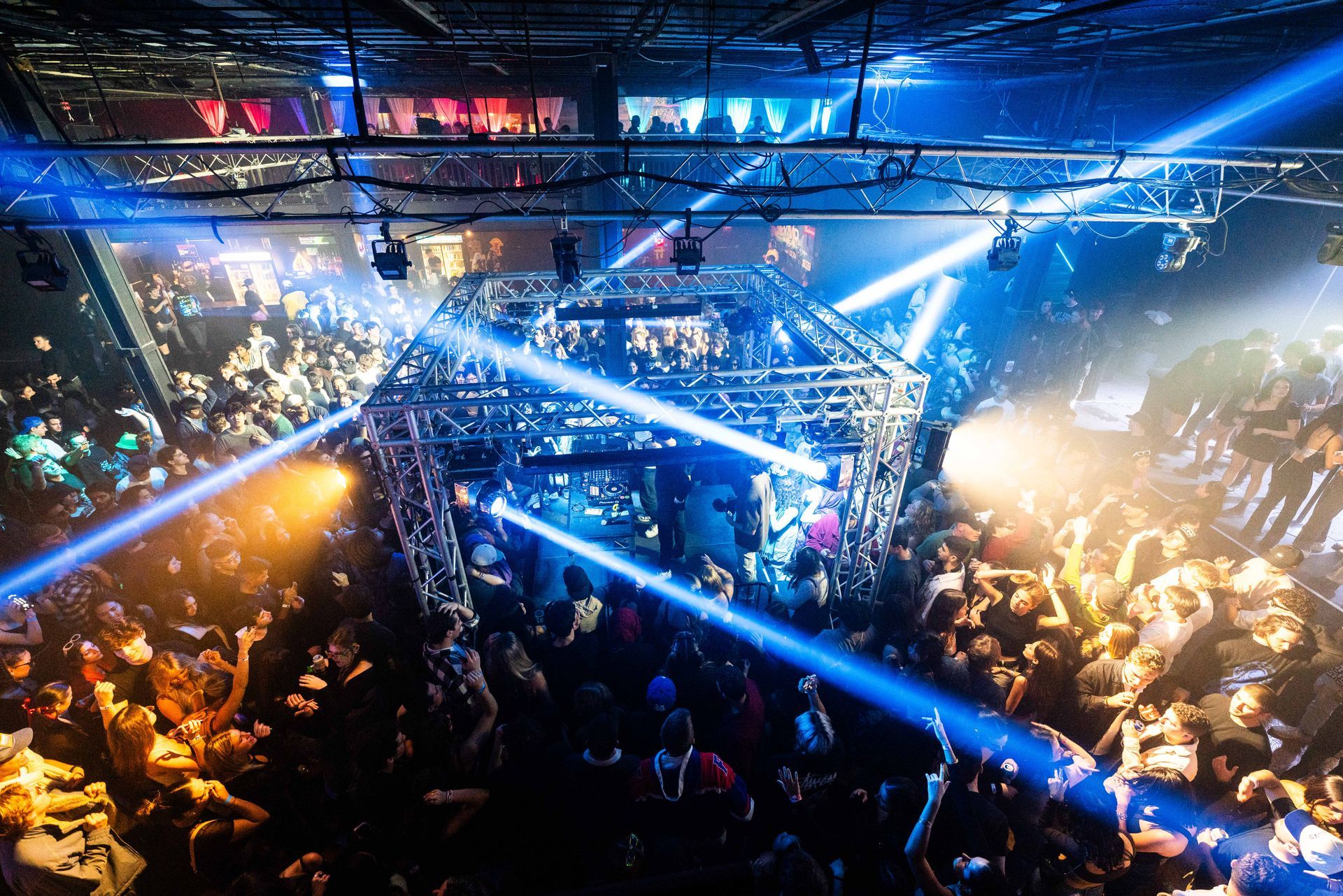 A crowd of people are dancing in a club with blue lights shining on them