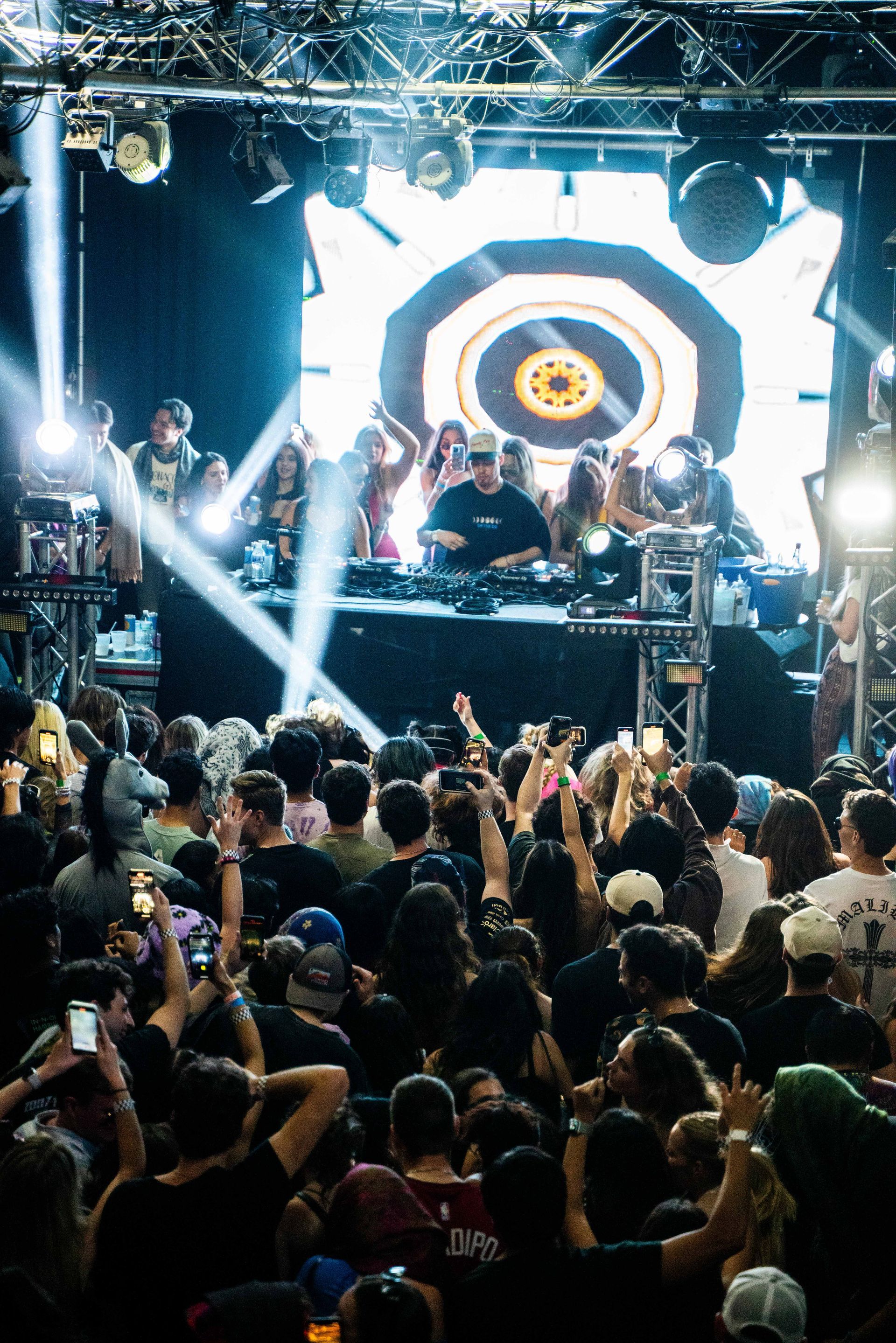 A crowd of people are standing in front of a stage at a concert.
