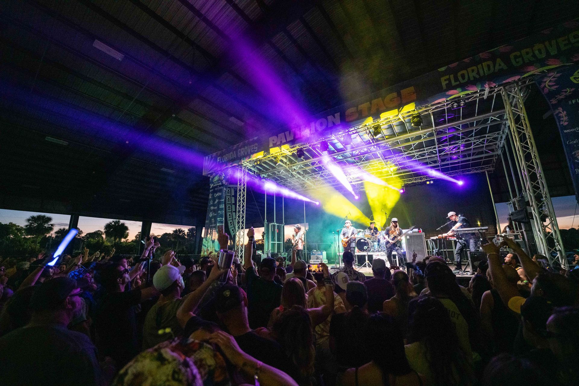 A crowd of people are standing in front of a stage at a concert.
