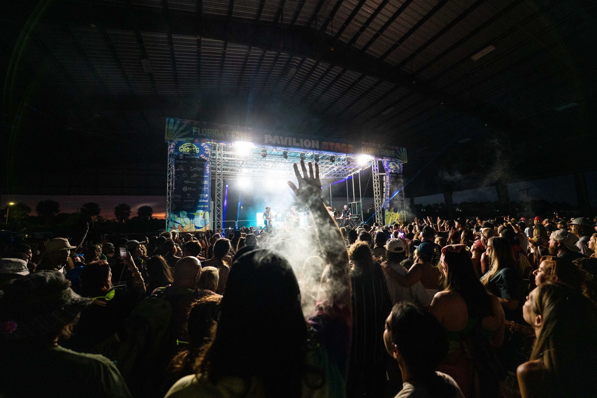 A crowd of people are standing in front of a stage at a concert.