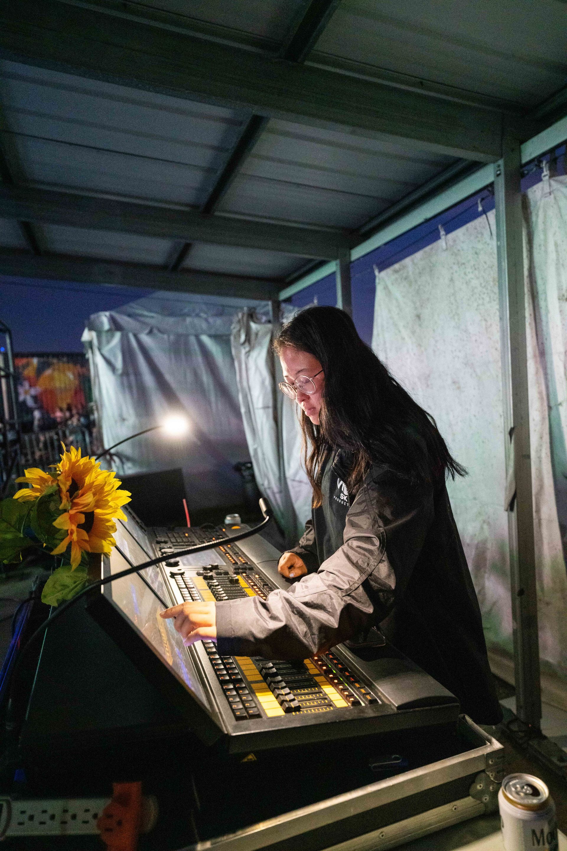 A woman is working on a sound board in a dark room.