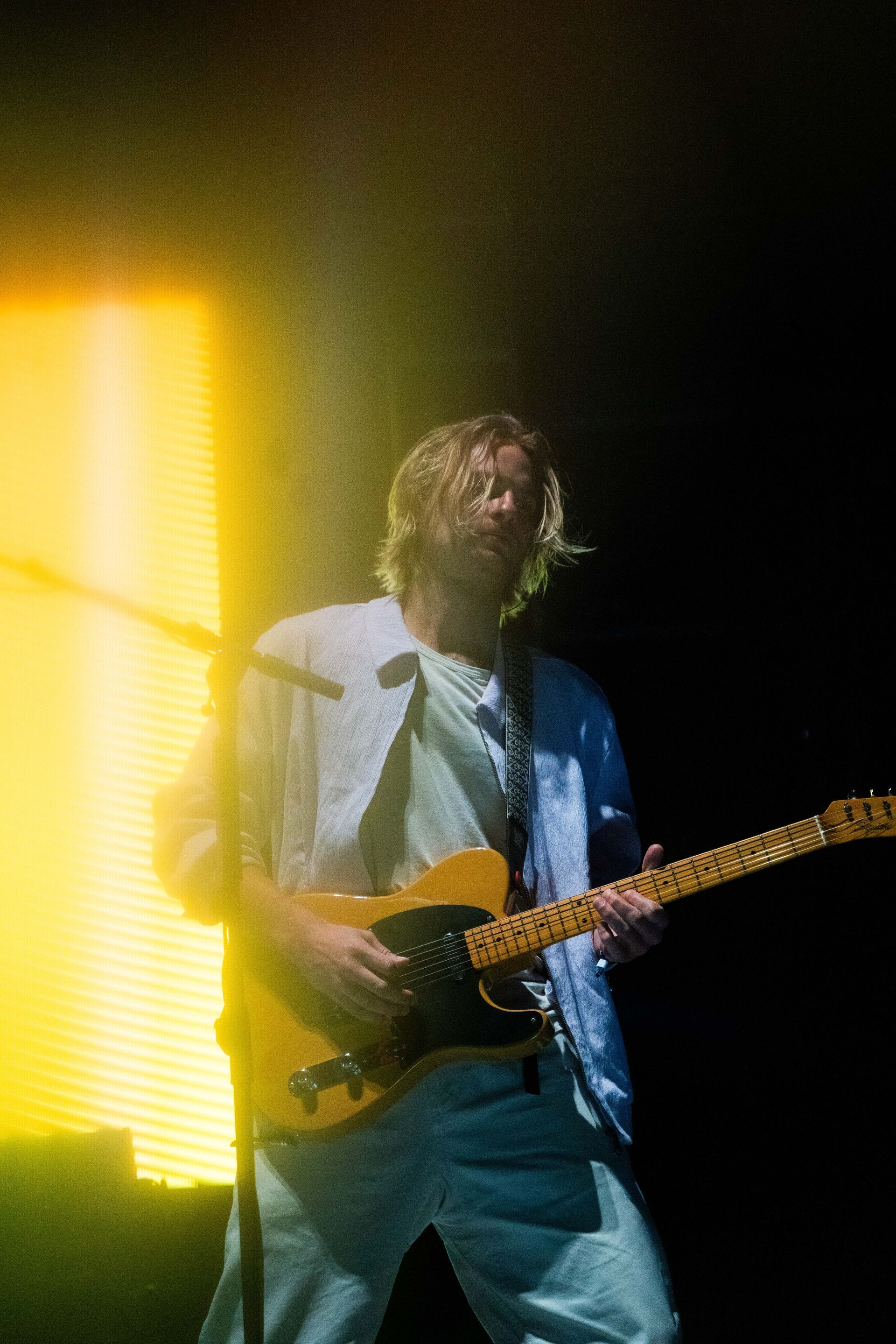 A man is playing a guitar and singing into a microphone on a stage.