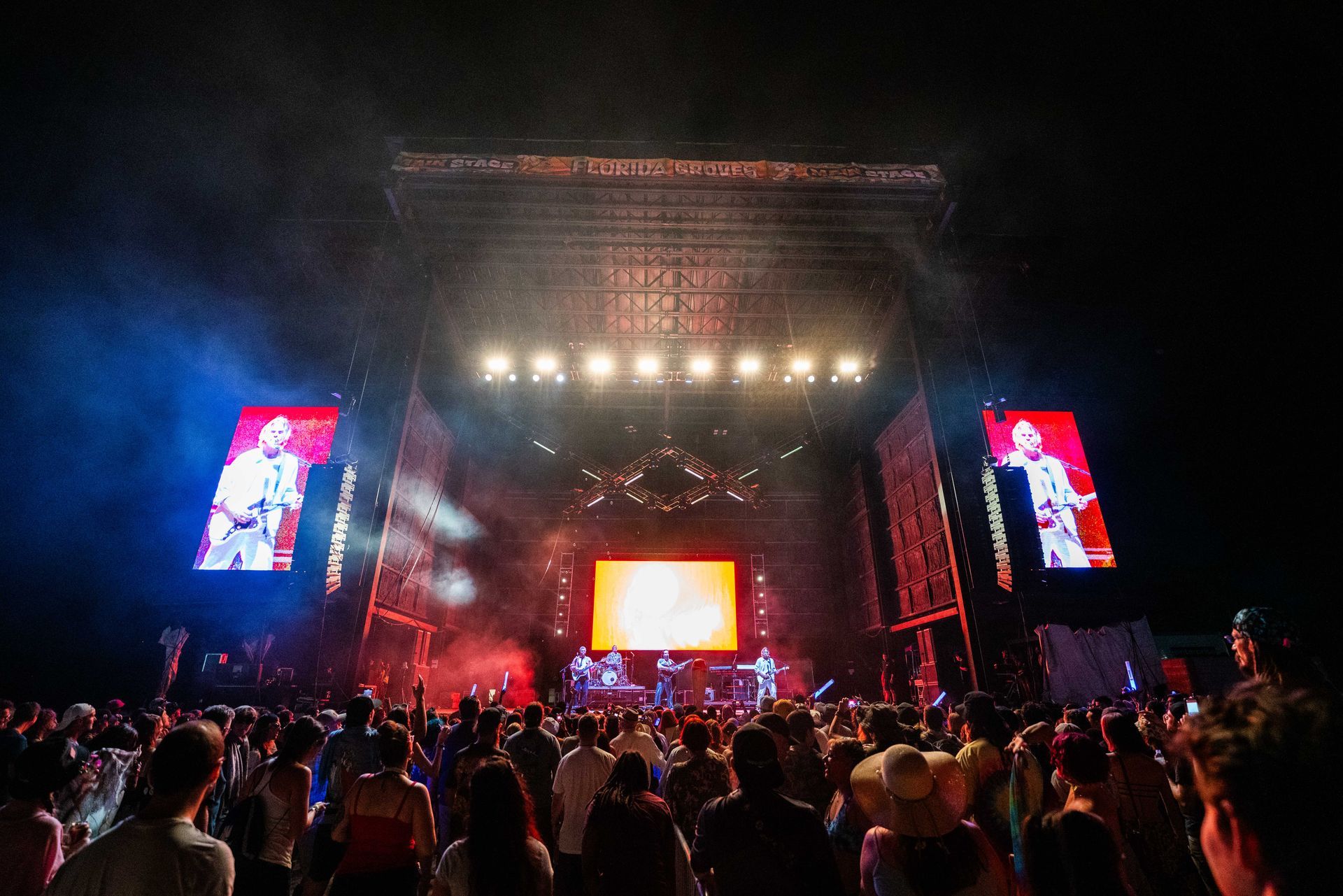 A crowd of people are standing in front of a stage at a concert.