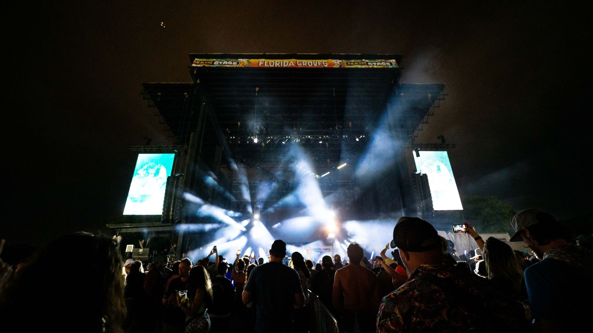 A crowd of people are standing in front of a stage at a concert.
