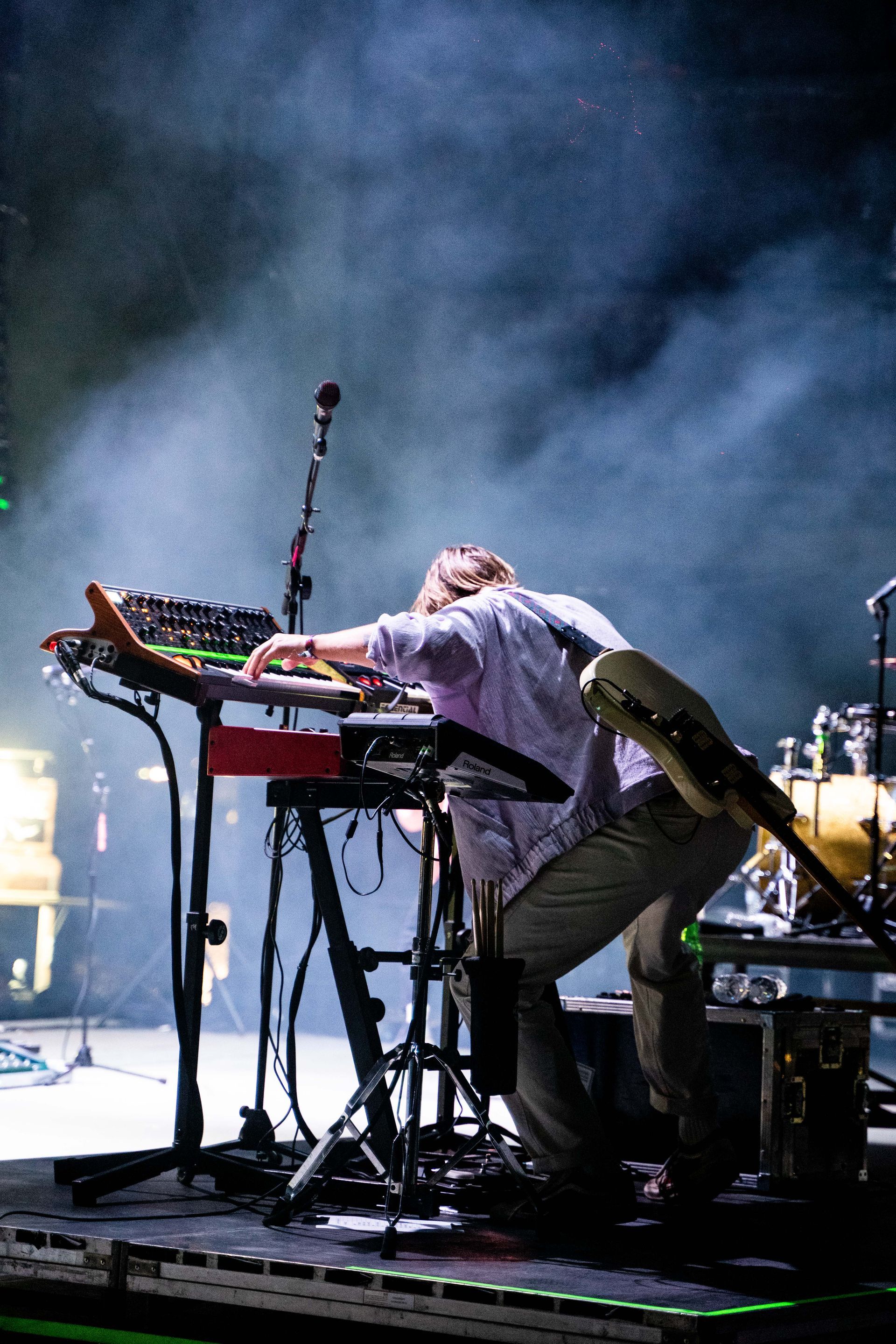 A man is playing a keyboard on a stage in front of a microphone