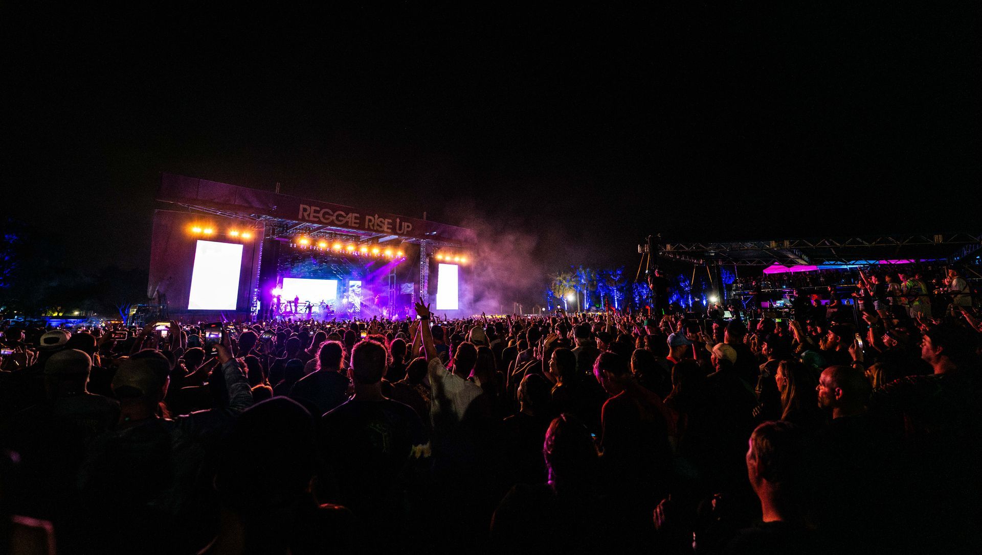 A crowd of people are watching a concert at night.
