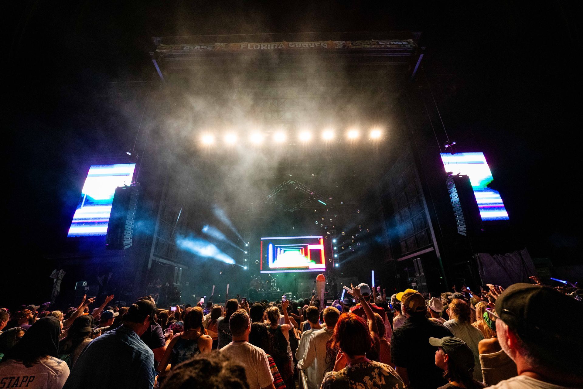 A crowd of people are standing in front of a stage at a concert.