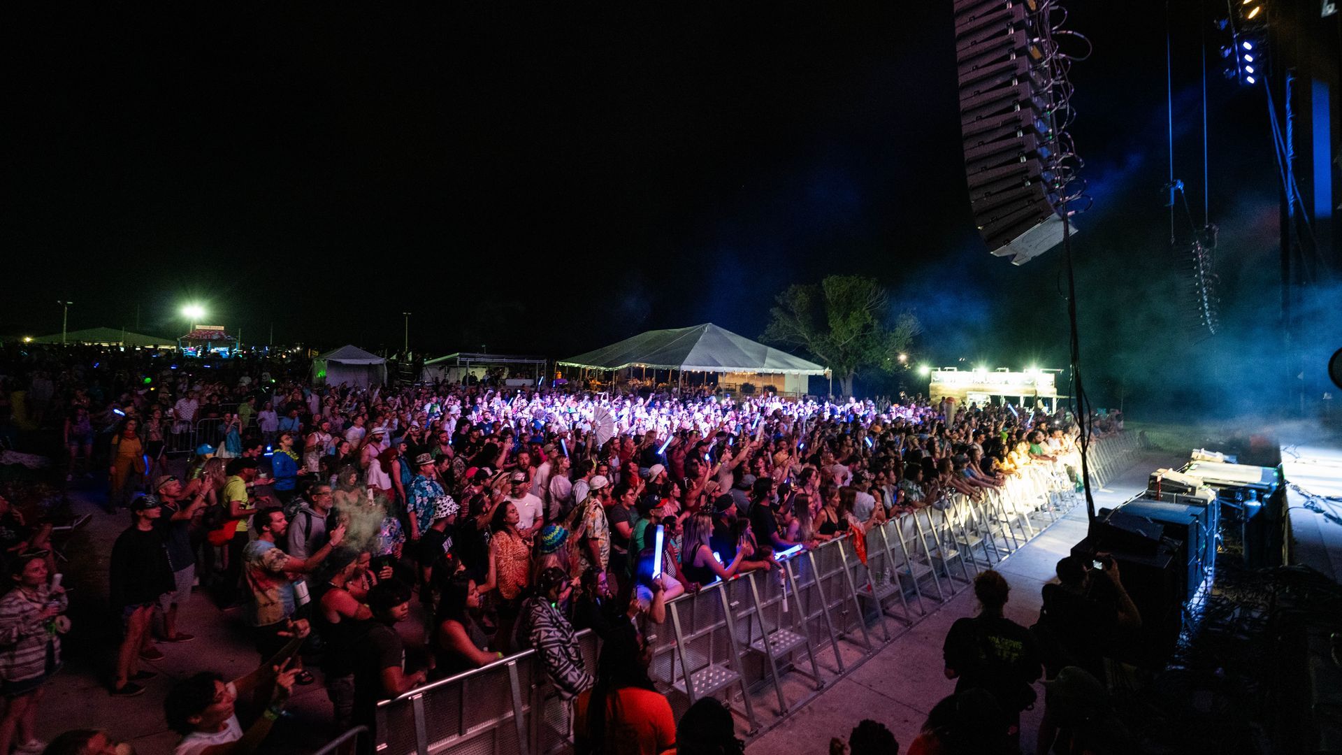 A large crowd of people are watching a concert at night.