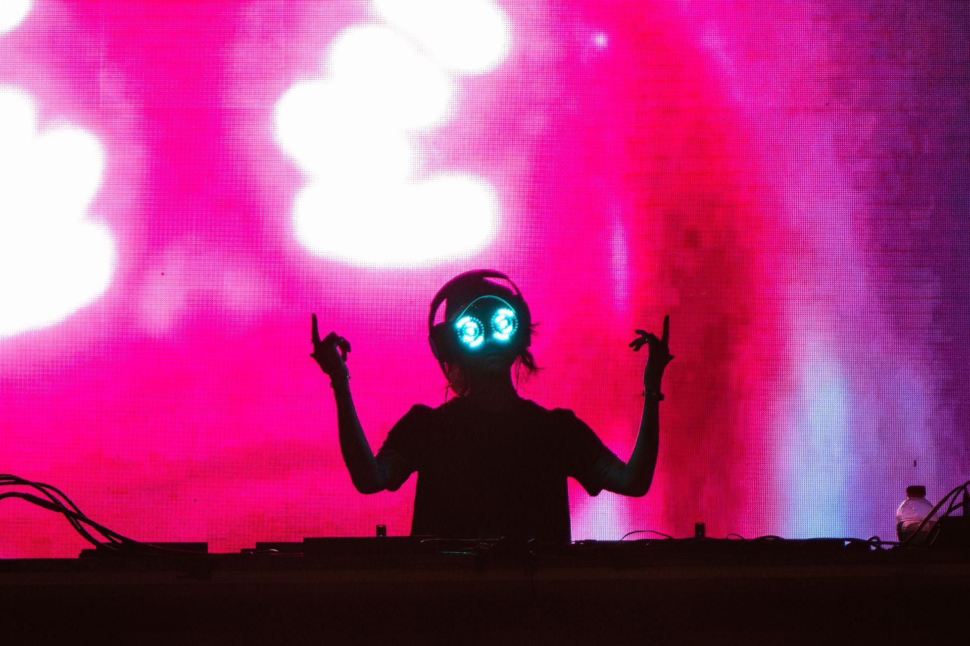 A silhouette of a person wearing headphones and a robot mask on a stage.