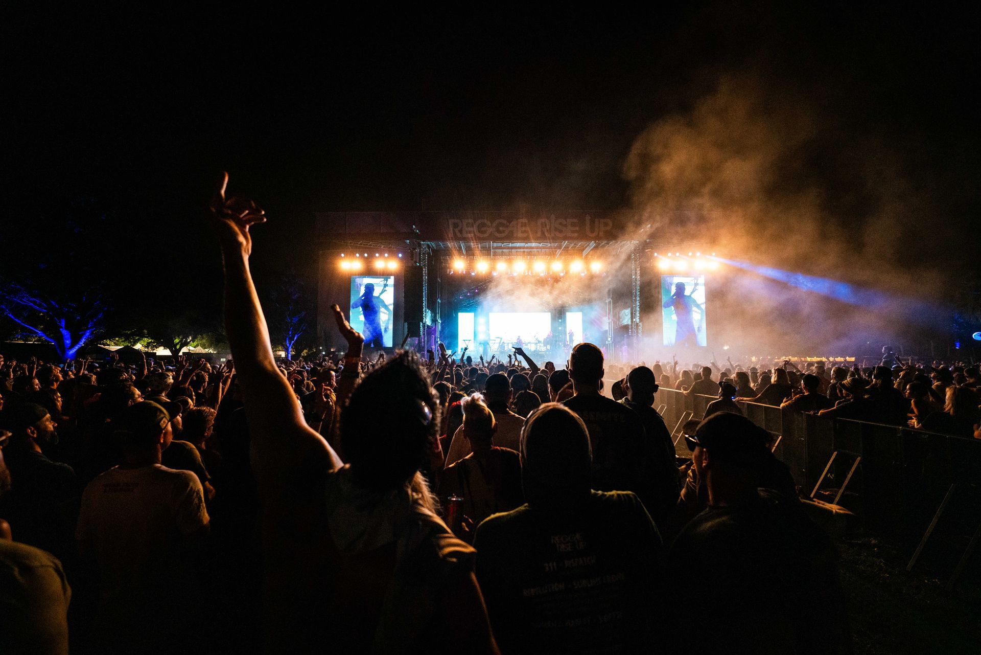 A crowd of people are watching a concert at night.