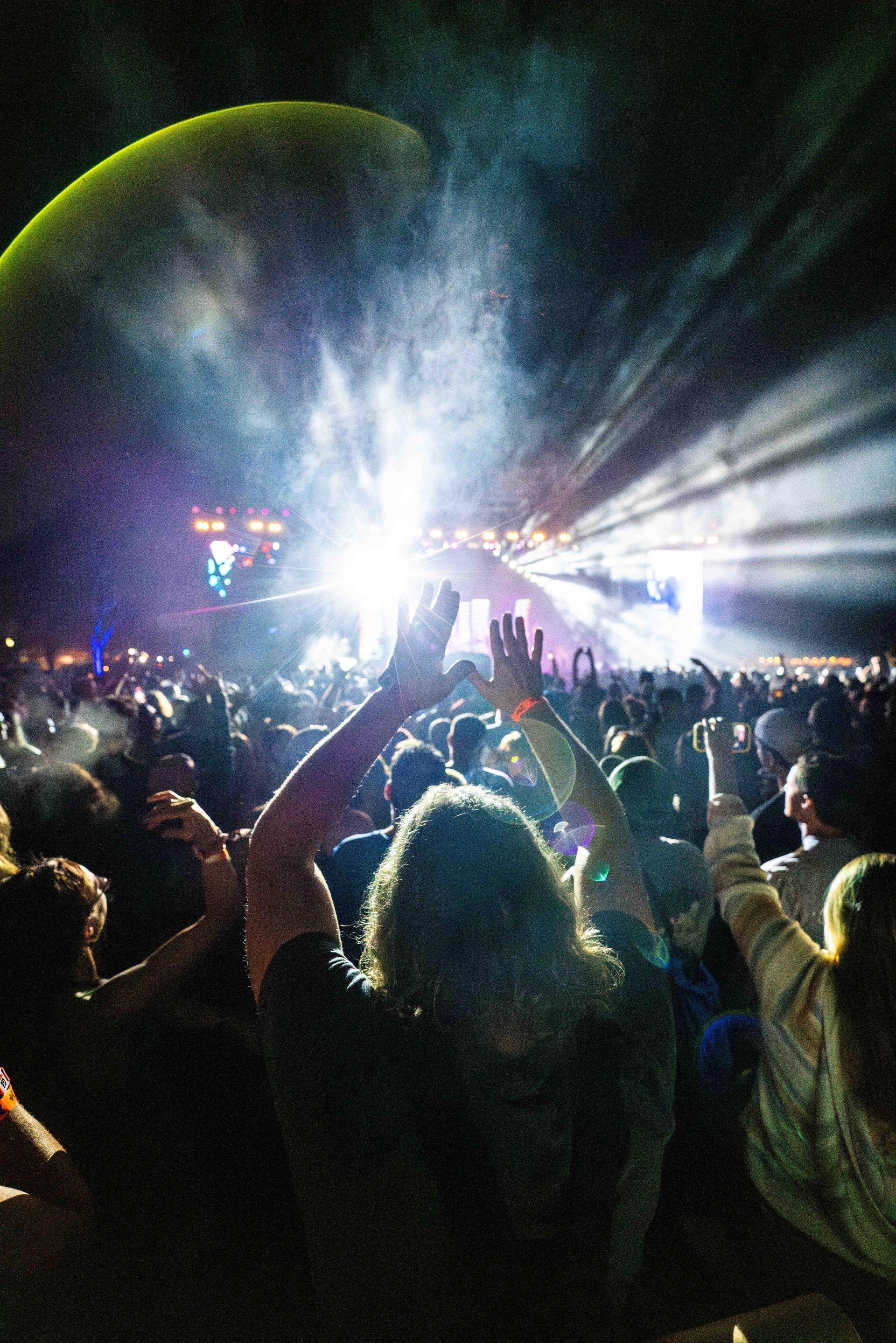 A crowd of people at a concert with their hands in the air.