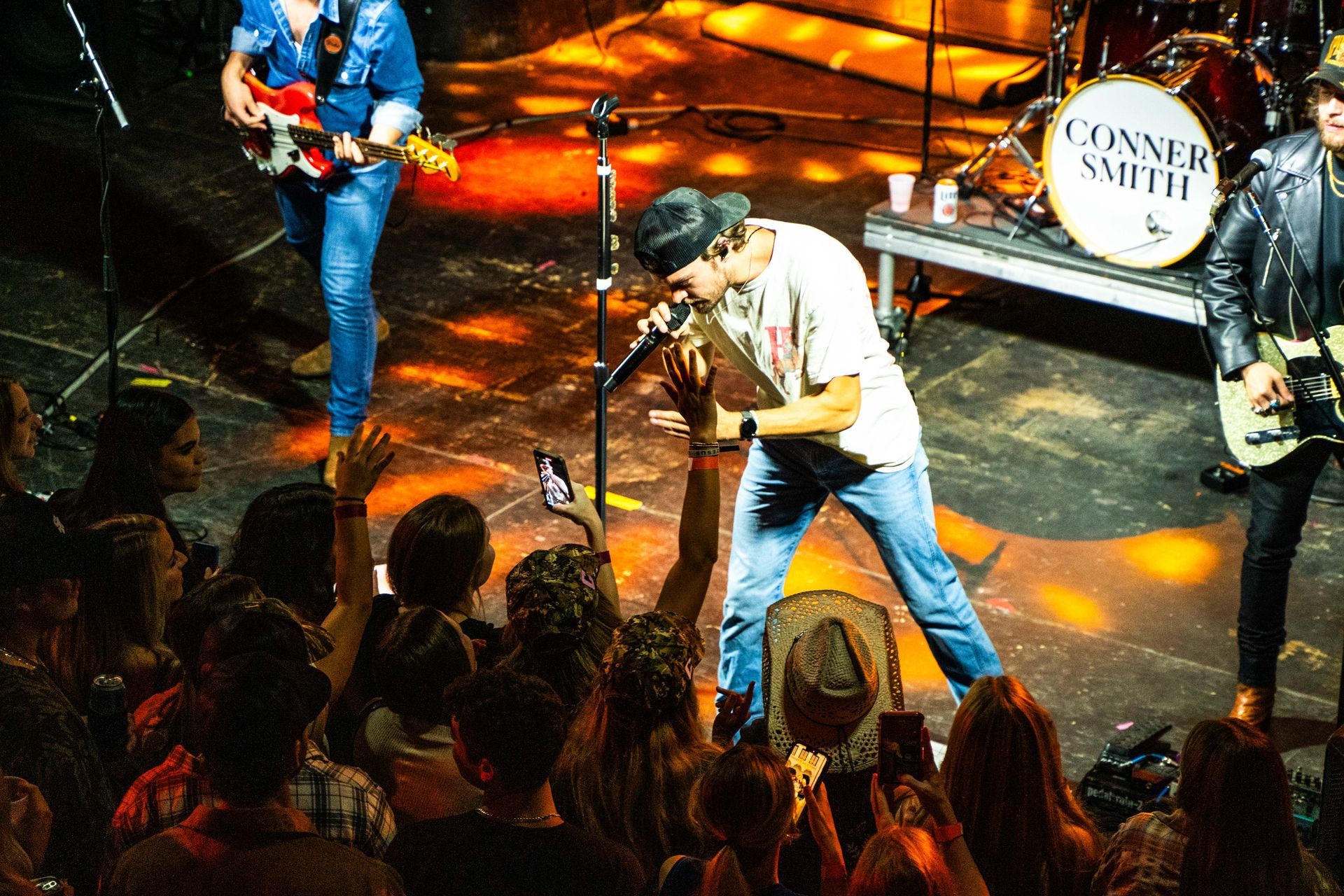 A man is singing into a microphone on a stage in front of a crowd.
