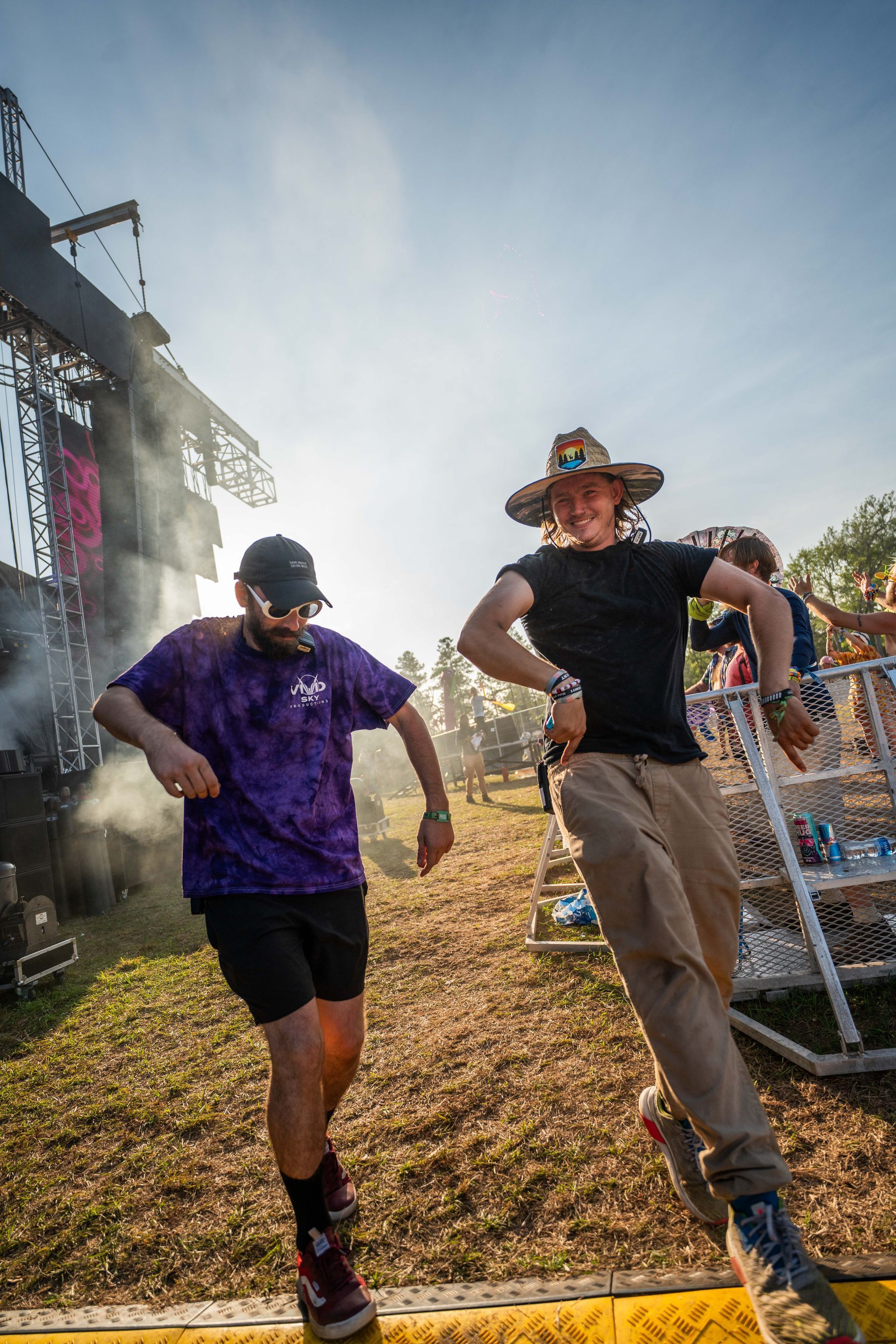 Two men are dancing in front of a stage at a music festival.
