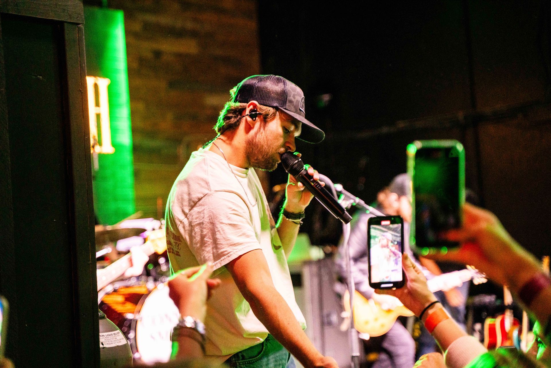 A man is singing into a microphone while a person takes a picture of him.