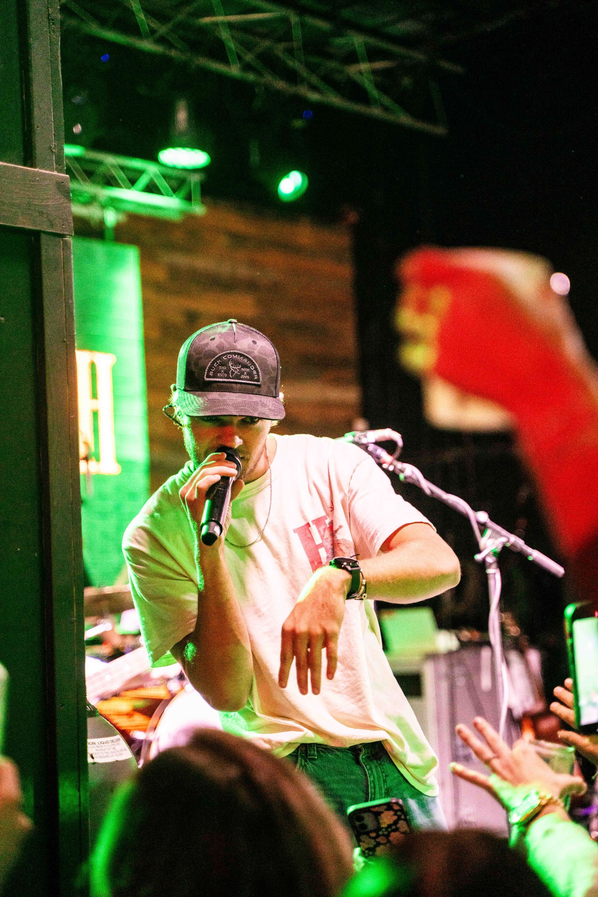 A man is singing into a microphone on stage in front of a crowd.