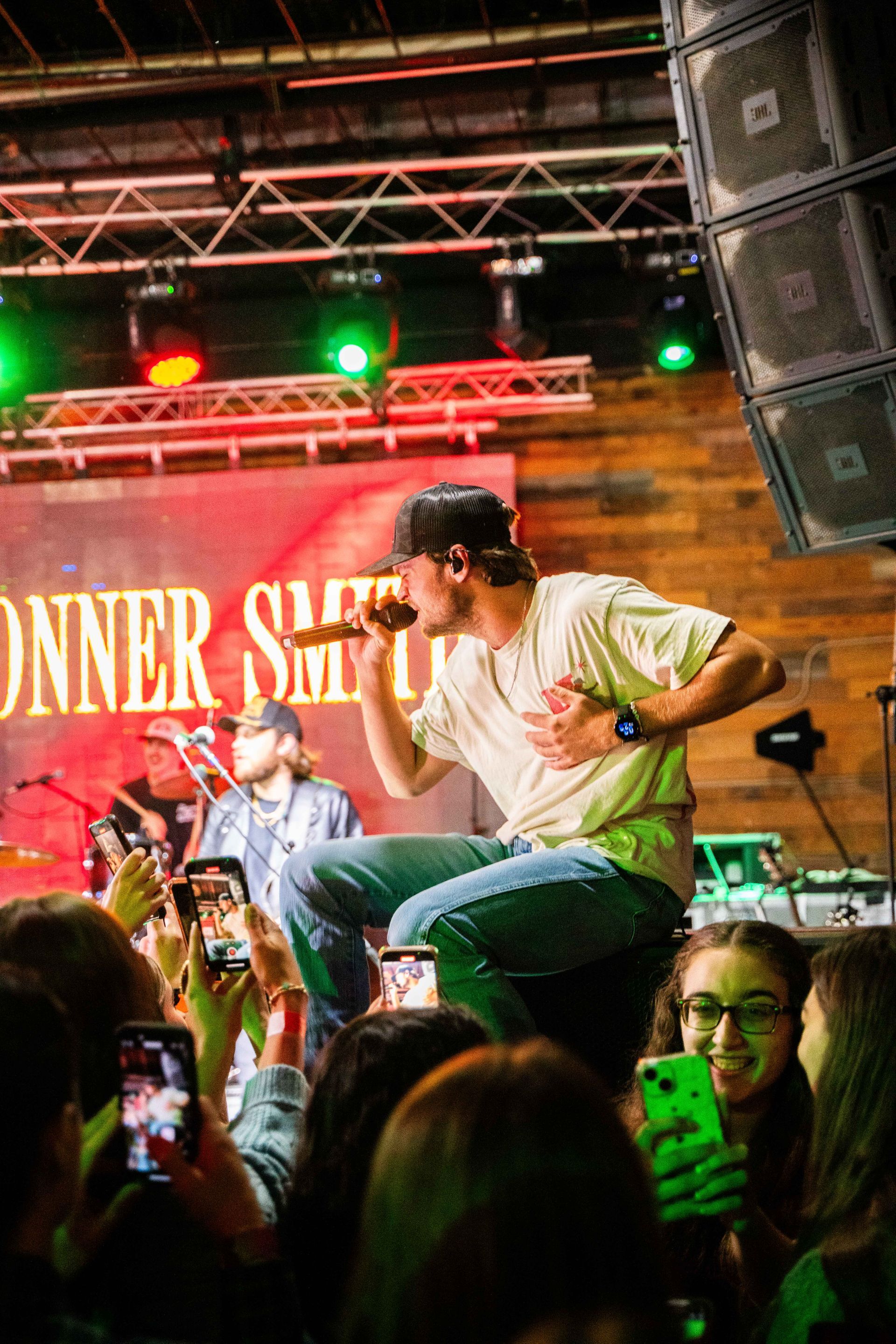 A man is singing into a microphone on a stage in front of a crowd.