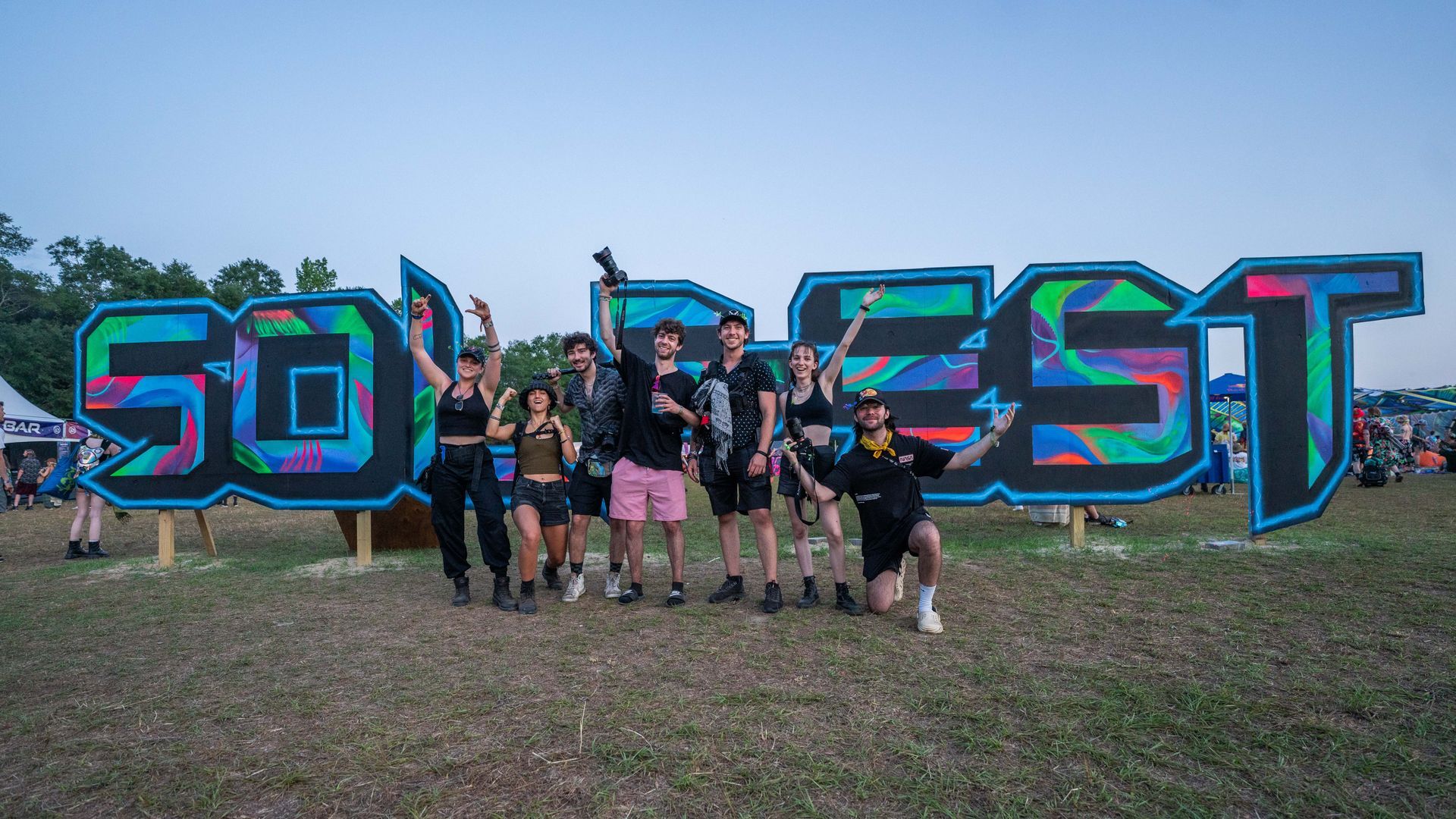 A group of people are posing for a picture in front of a sign that says sofest.