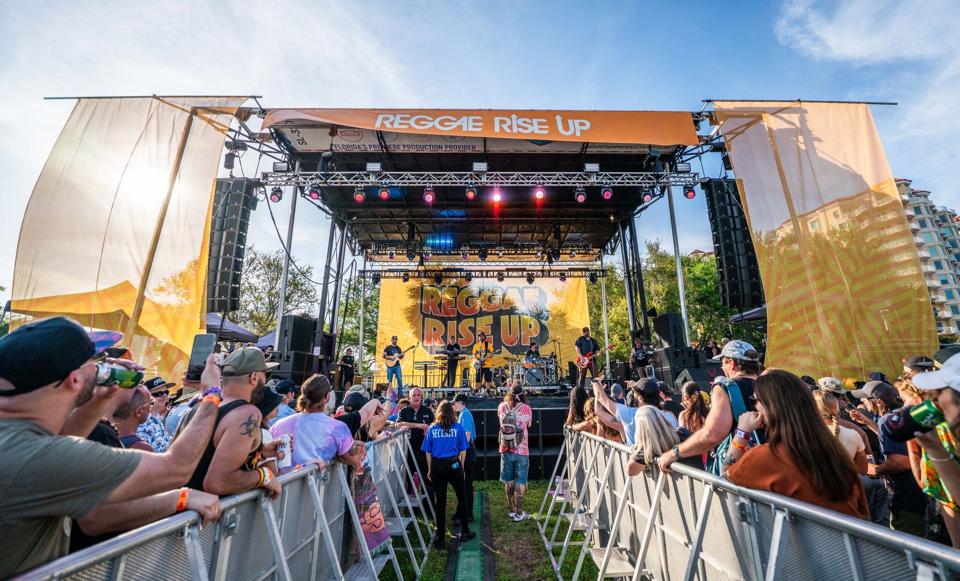 A crowd of people are standing in front of a stage at a music festival.