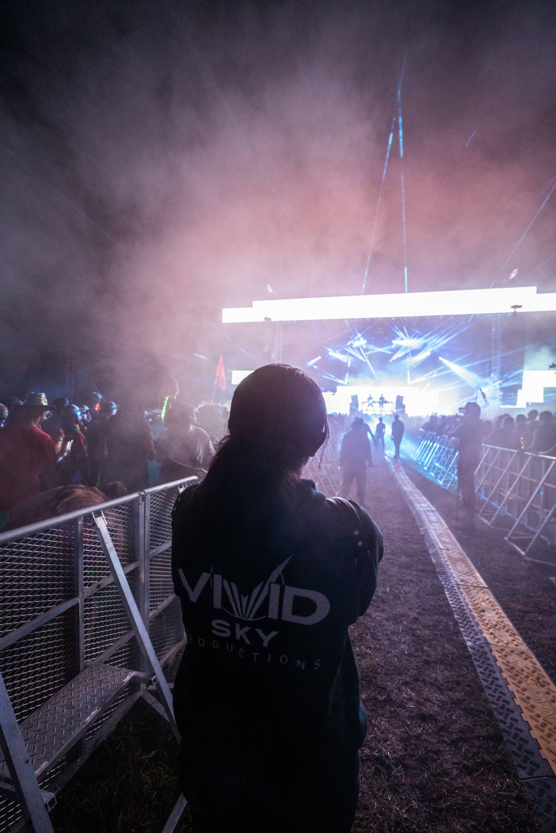 A person is standing in front of a crowd at a concert.