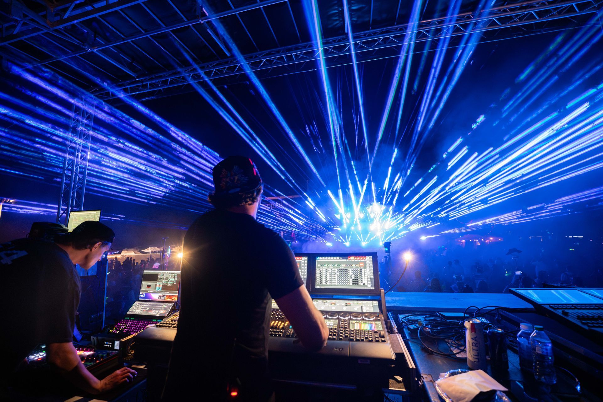 A dj is playing music in a dark room with blue lights coming out of the ceiling