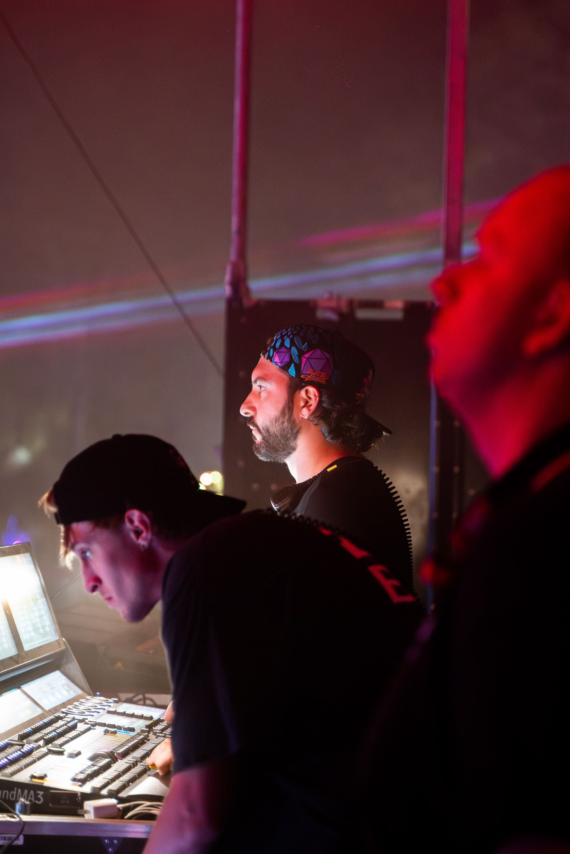 Two men are sitting in front of a computer in a dark room.