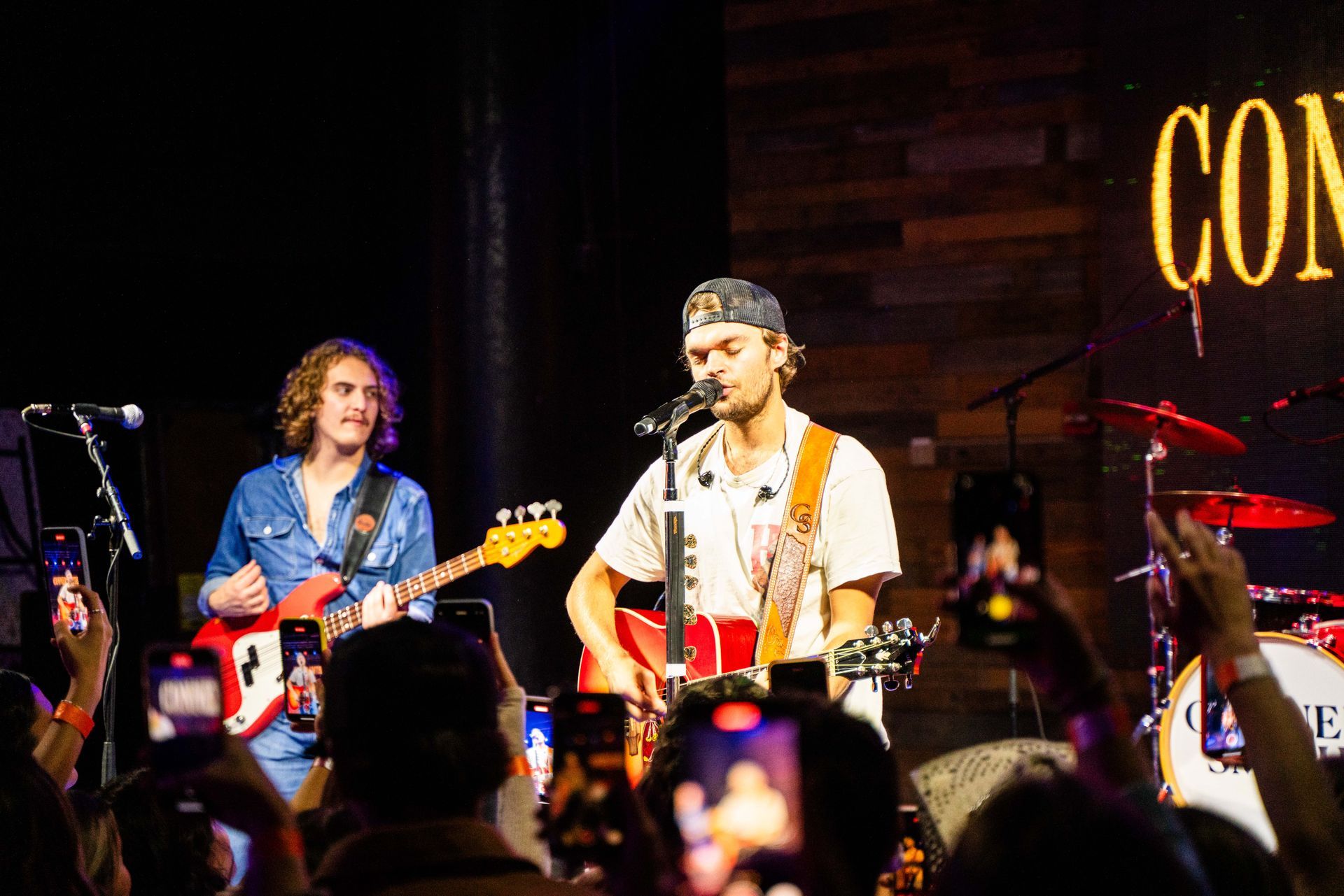 A man is playing a guitar and singing into a microphone on a stage.