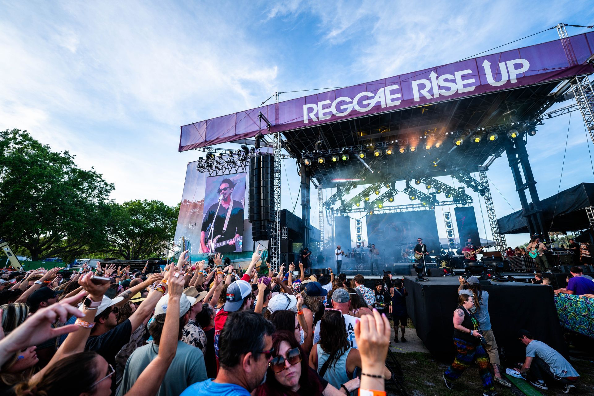 A crowd of people are watching a concert at a reggae rise up festival.