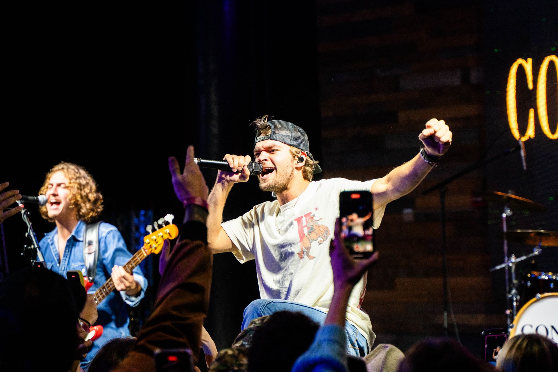 A man is singing into a microphone on a stage in front of a crowd.