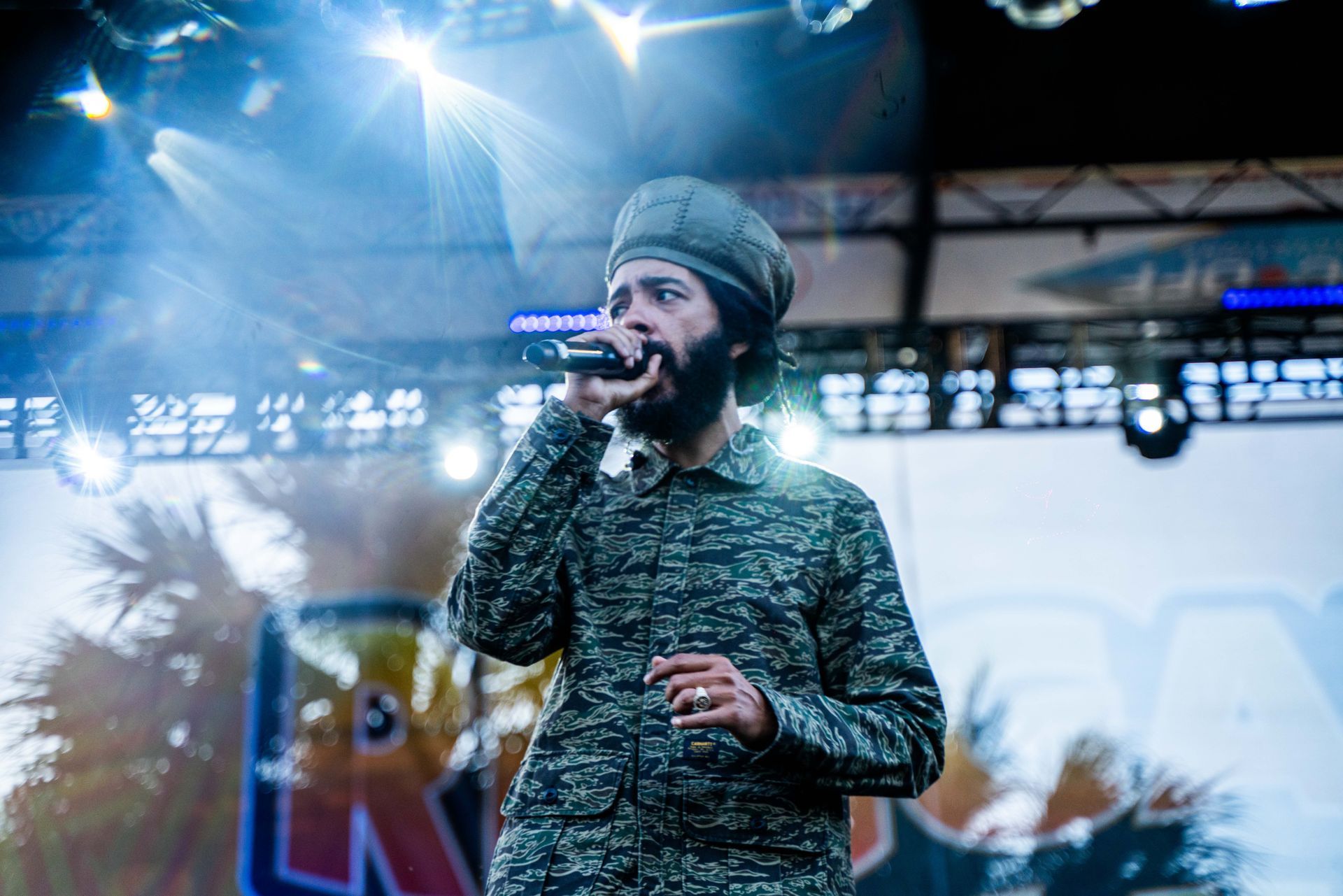 A man with a beard is singing into a microphone on a stage.