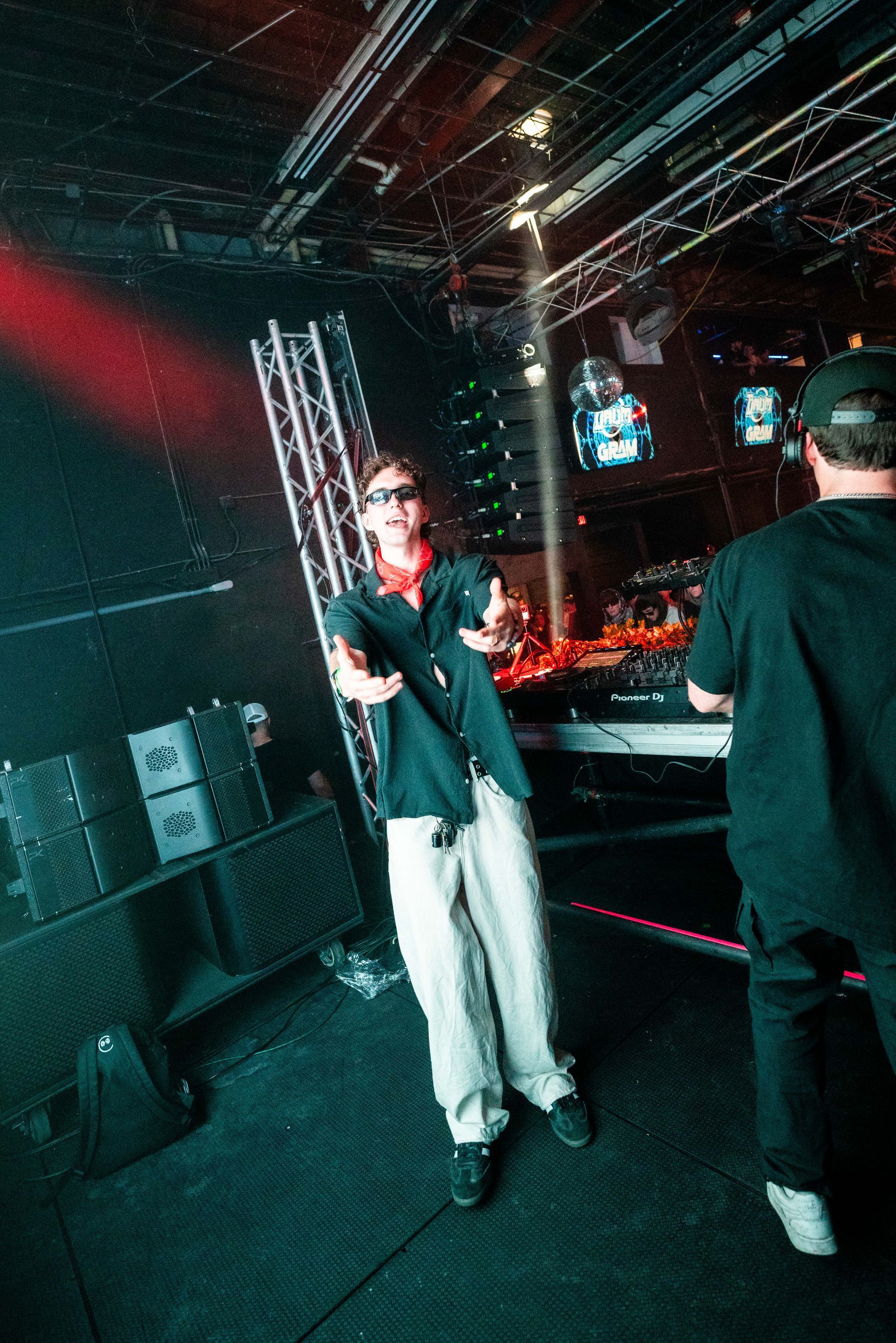 A man is standing on a stage in a dark room holding a microphone.
