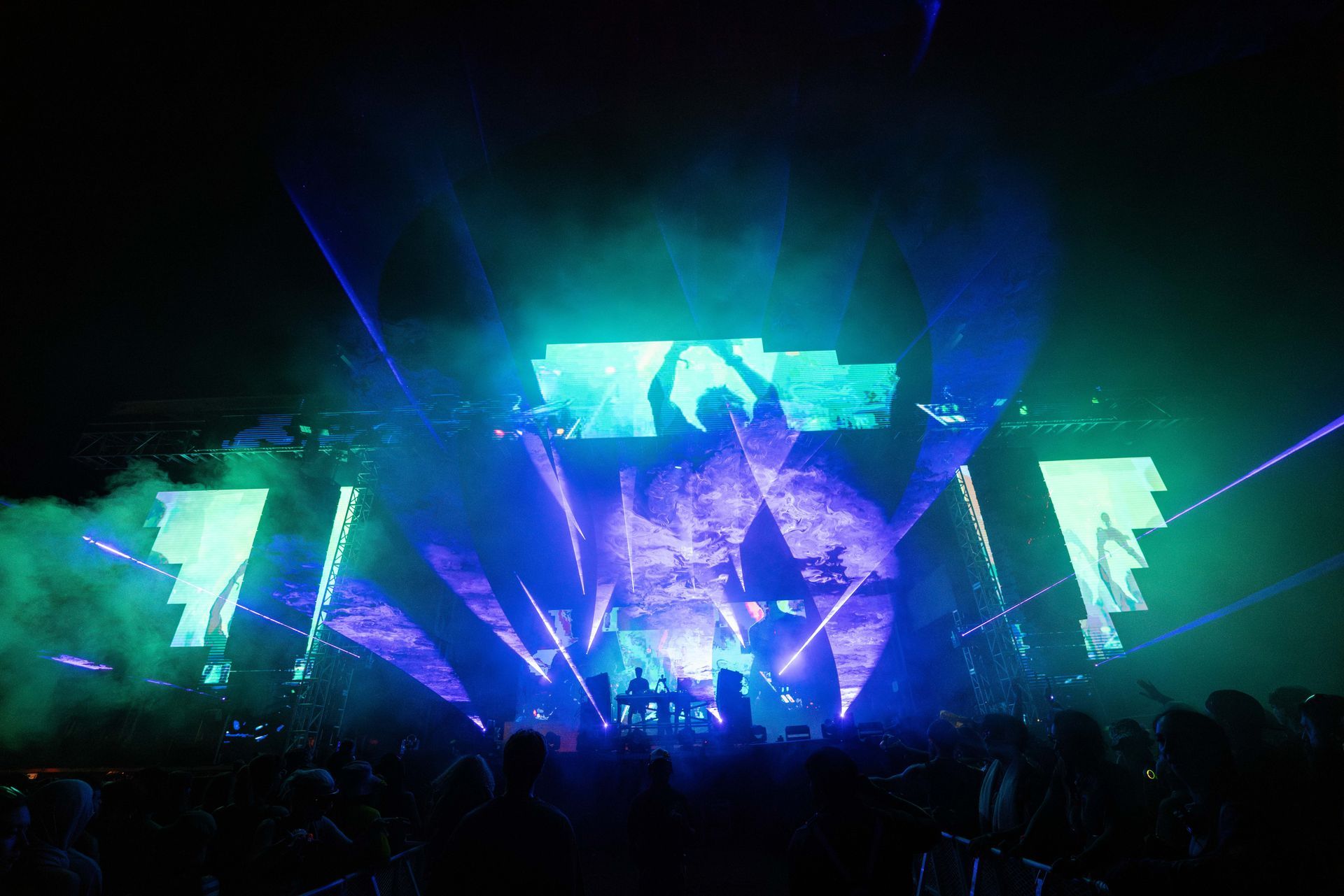 A crowd of people are standing in front of a stage at a concert.