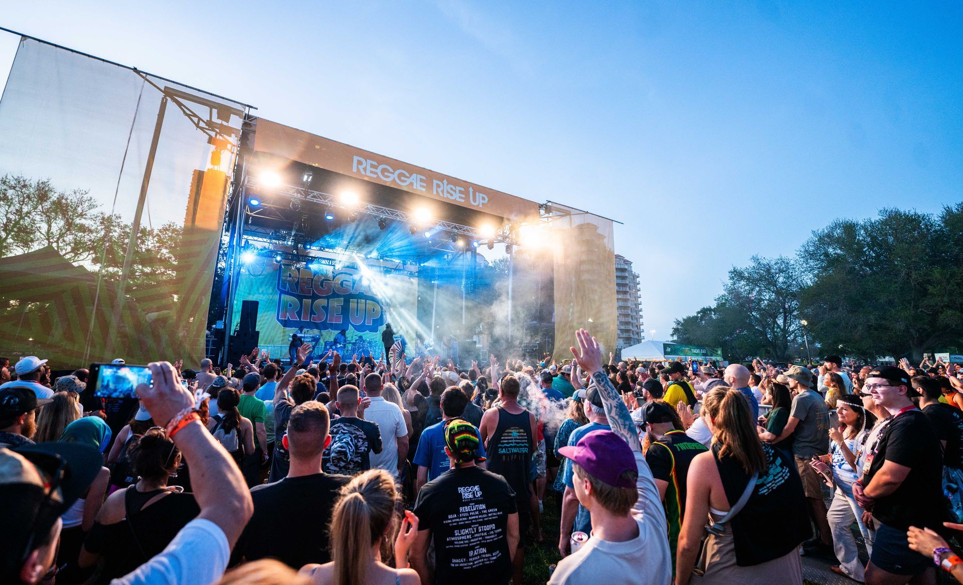 A crowd of people are standing in front of a stage at a concert.