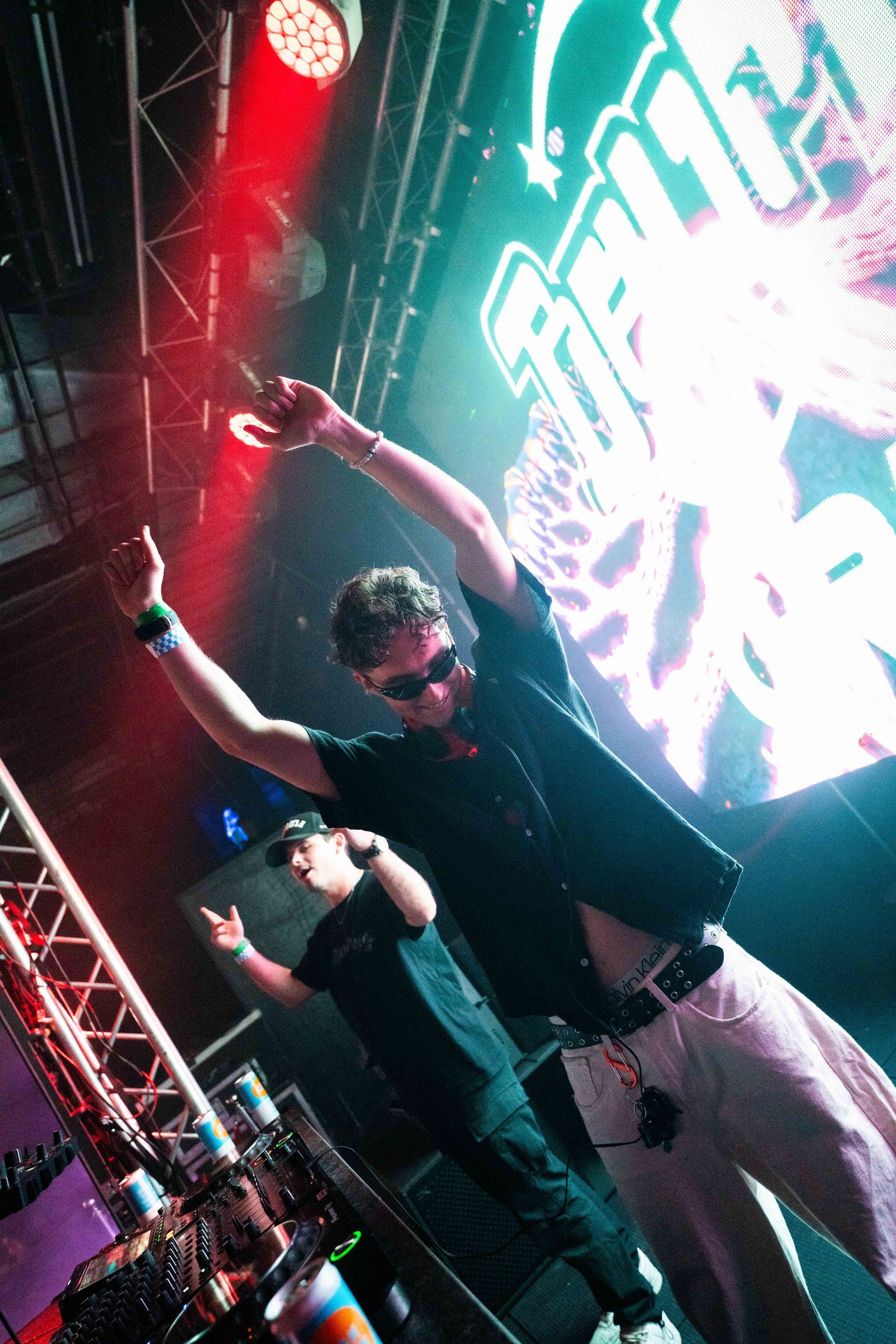 A man is standing on a stage with his arms in the air