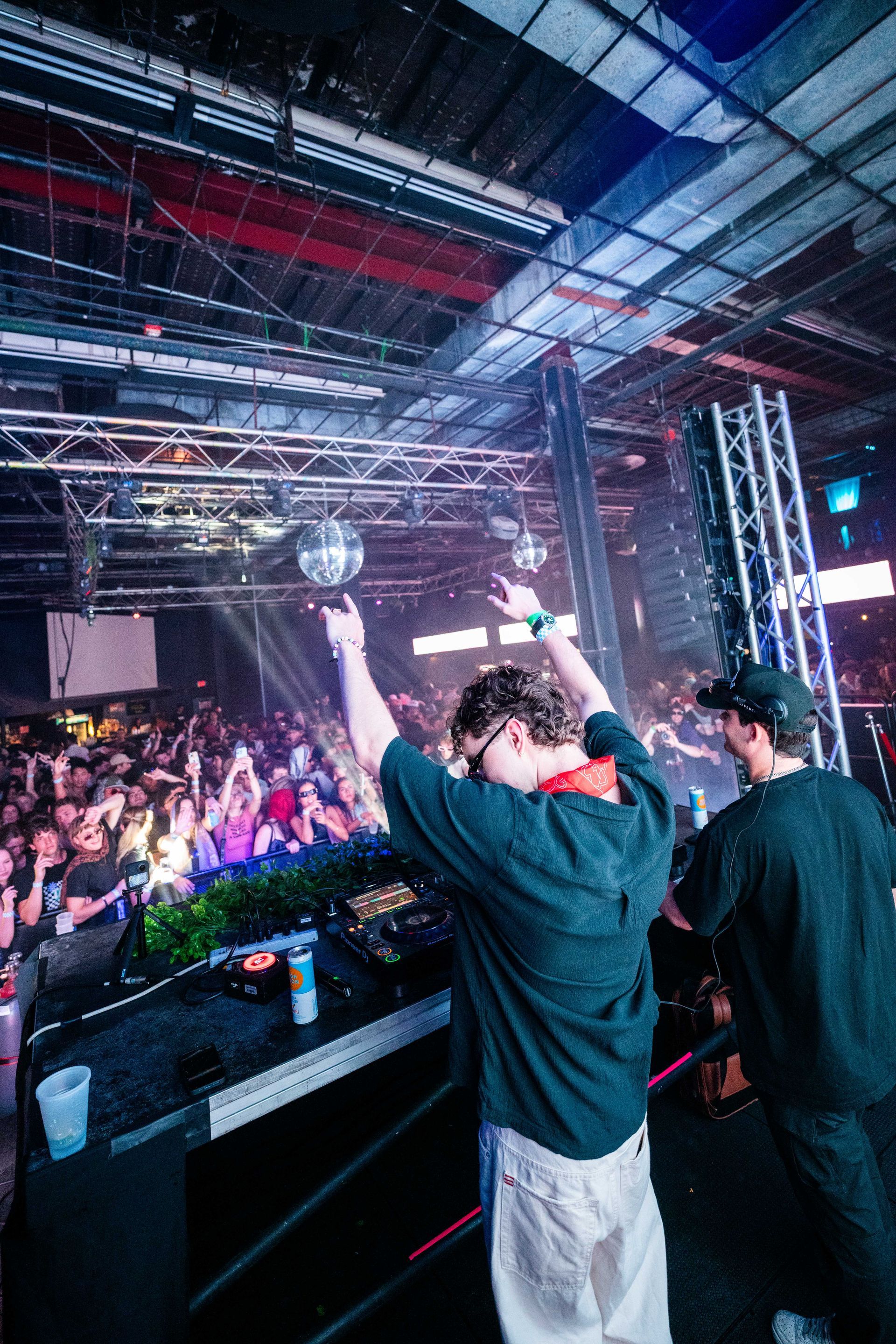 Two men are standing on a stage in front of a crowd at a concert.
