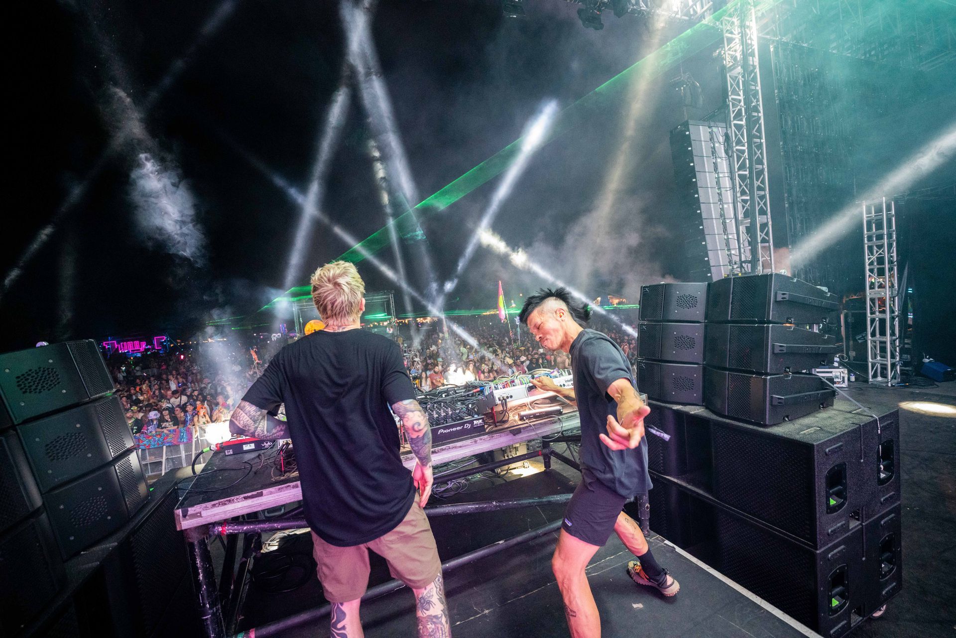 Two men are standing on a stage playing music.