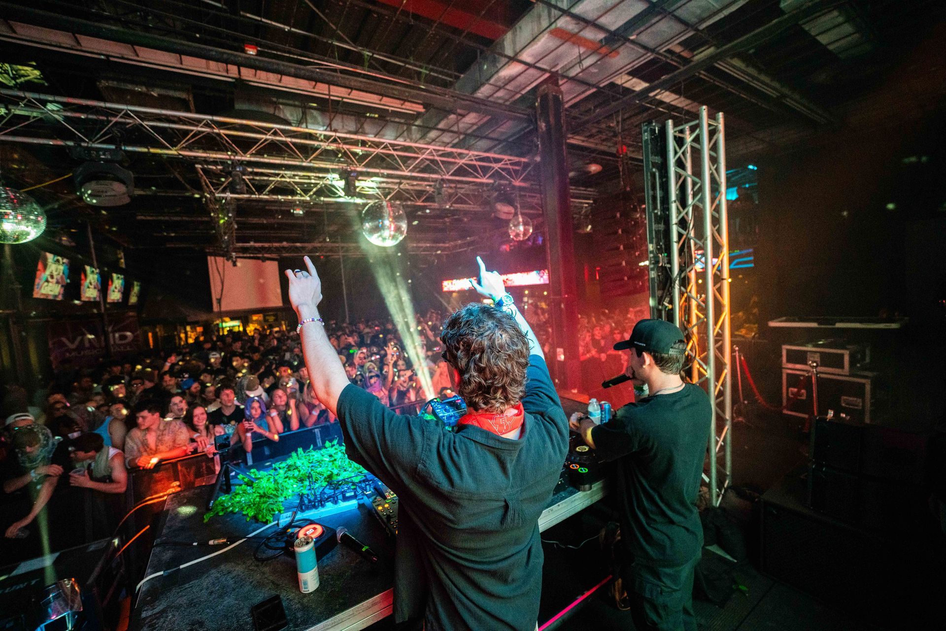 Two men are playing music on a stage in front of a crowd.