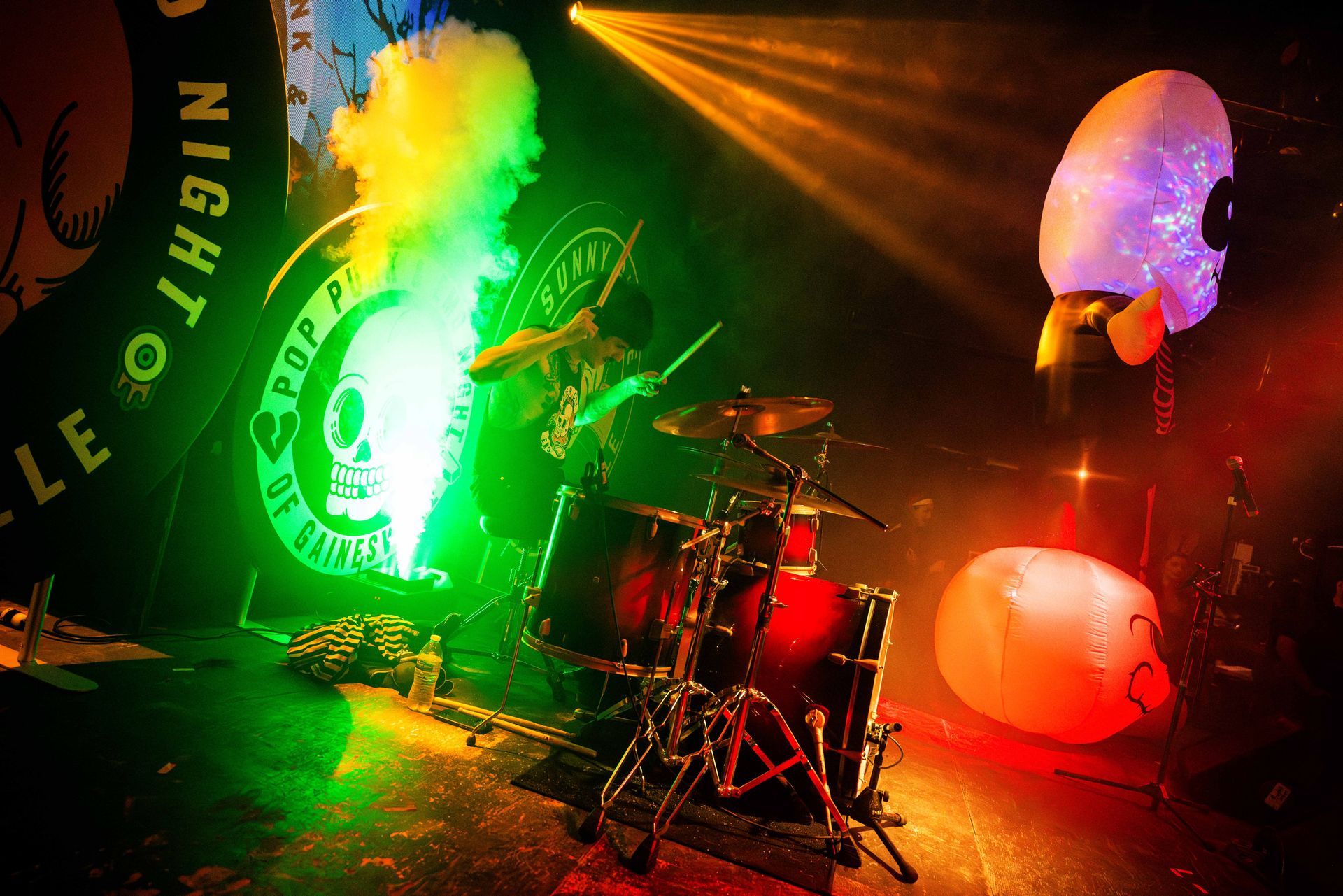 A man playing drums in front of a sign that says night on it