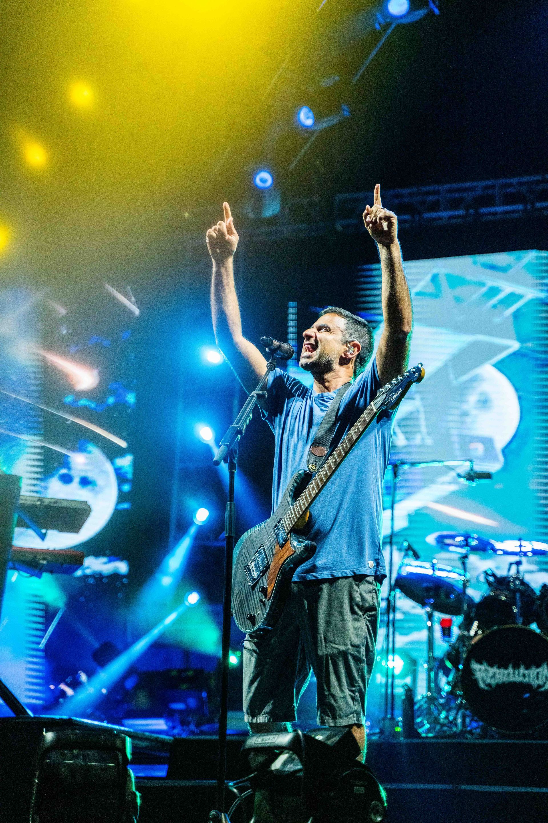 A man playing a guitar and singing into a microphone on a stage