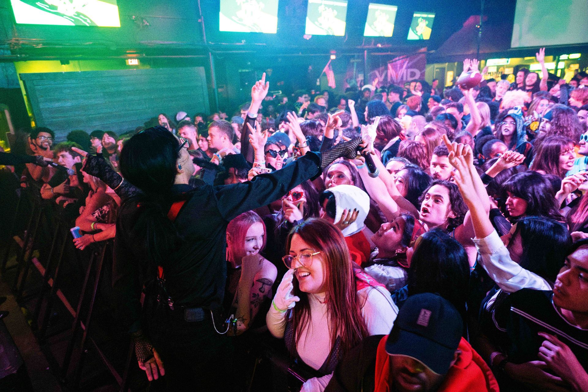 A crowd of people are dancing at a concert in a club.
