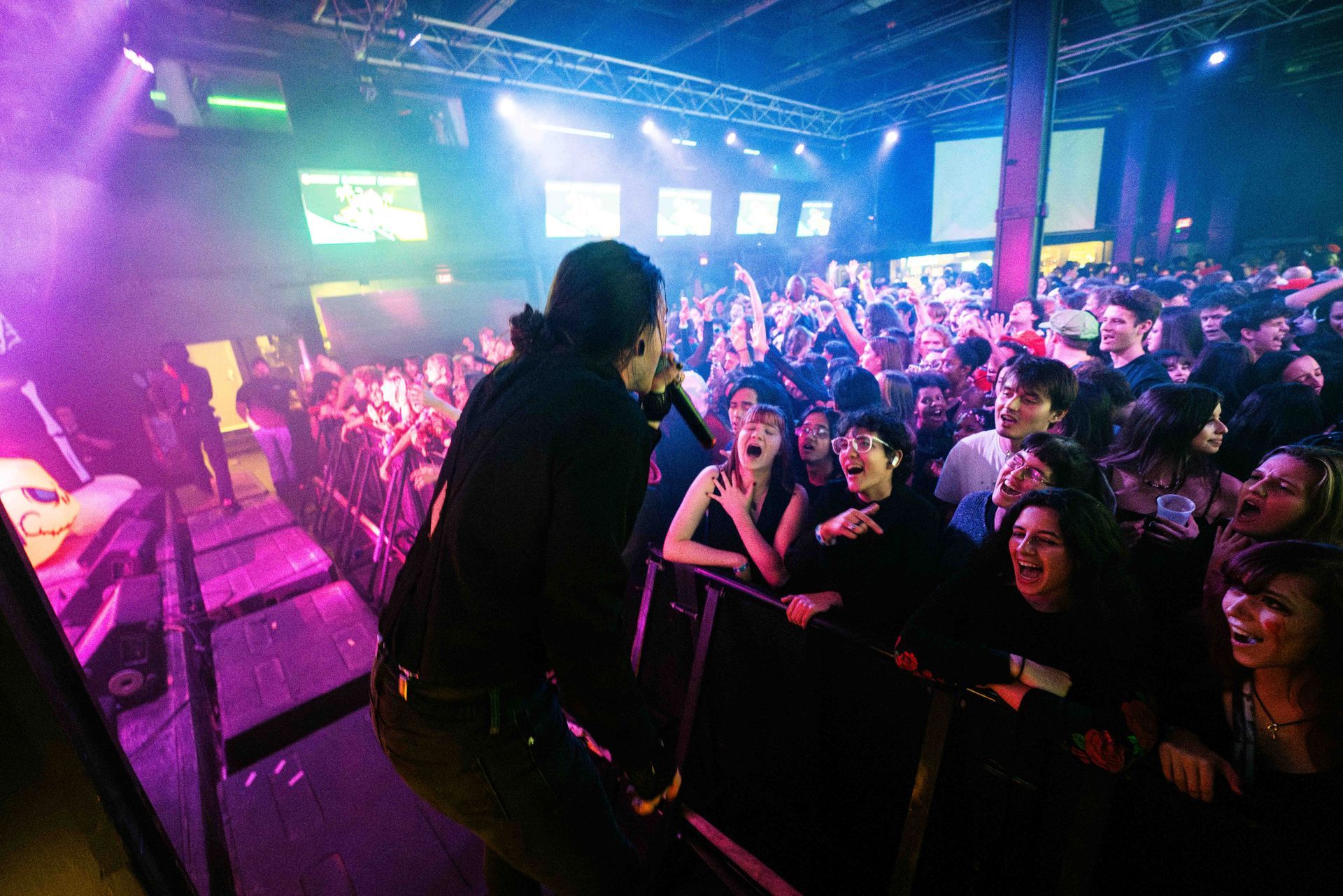 A man is singing into a microphone in front of a crowd at a concert.