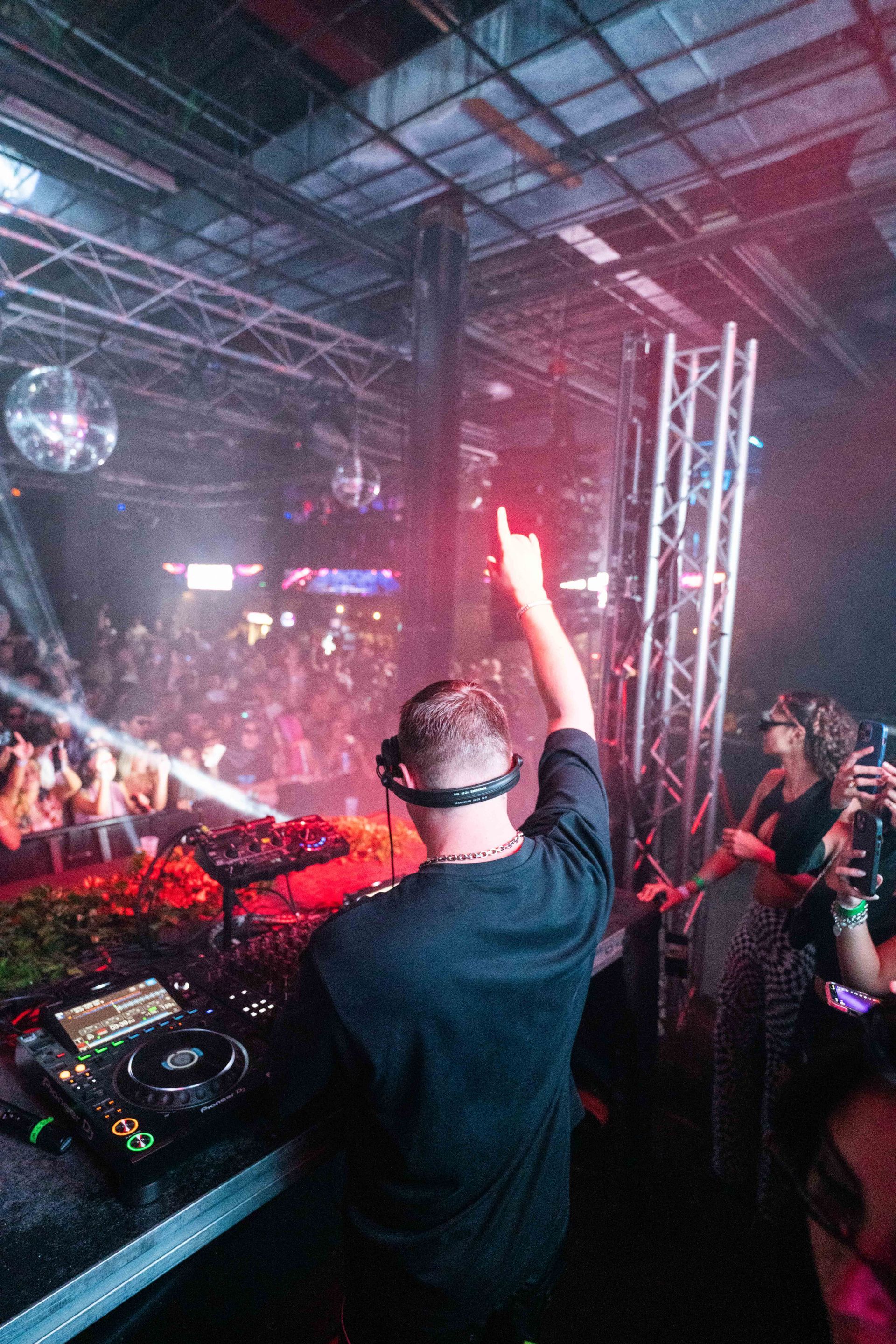 A dj is playing music at a party in front of a crowd.
