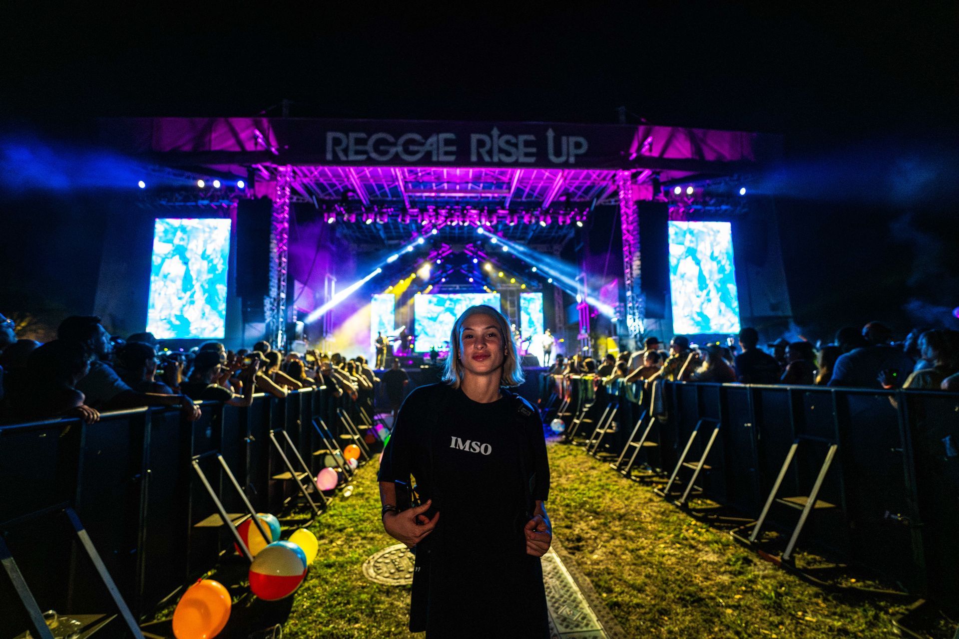 A woman is standing in front of a stage at a concert.