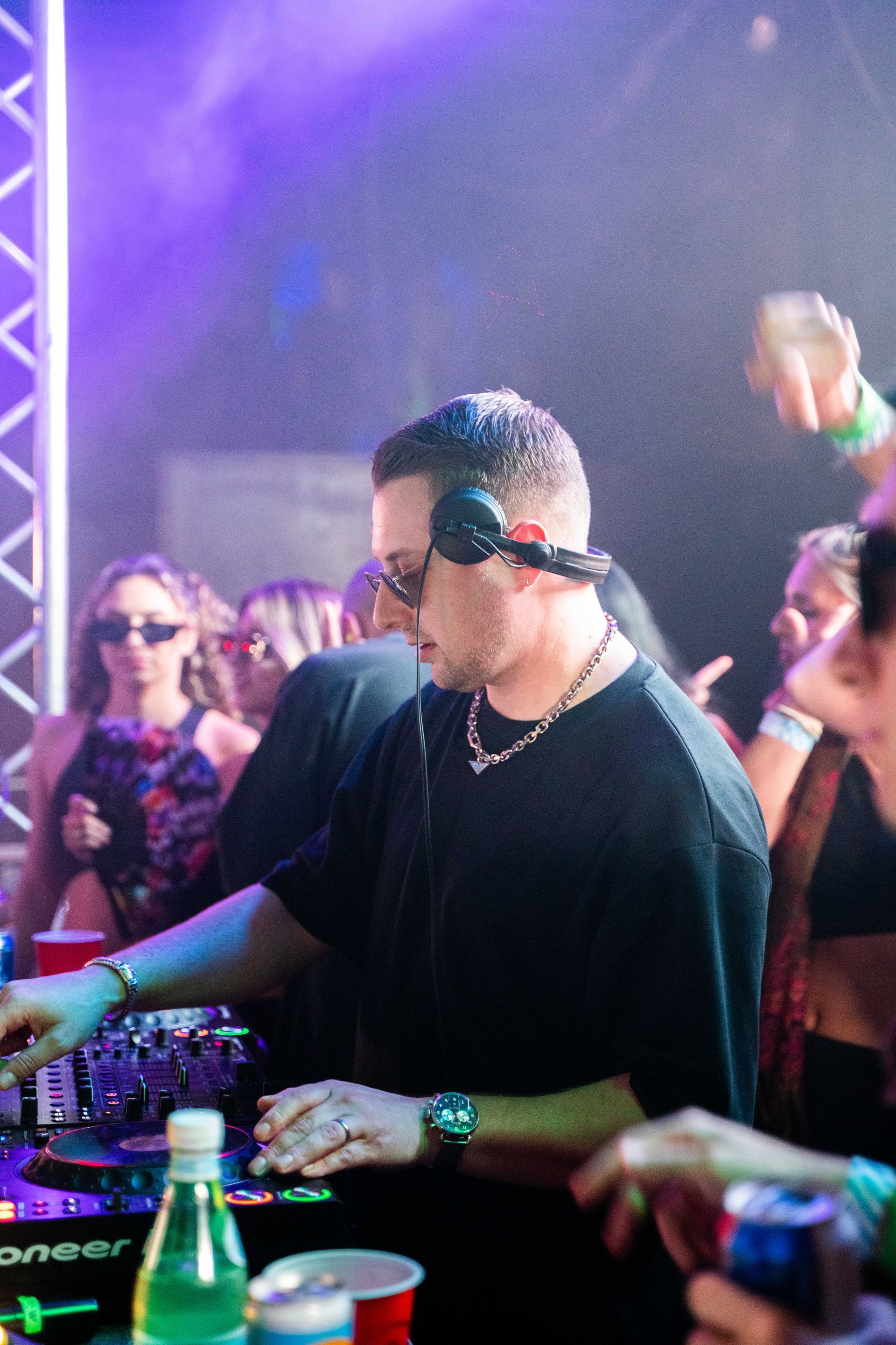 A man wearing headphones is playing music at a party.